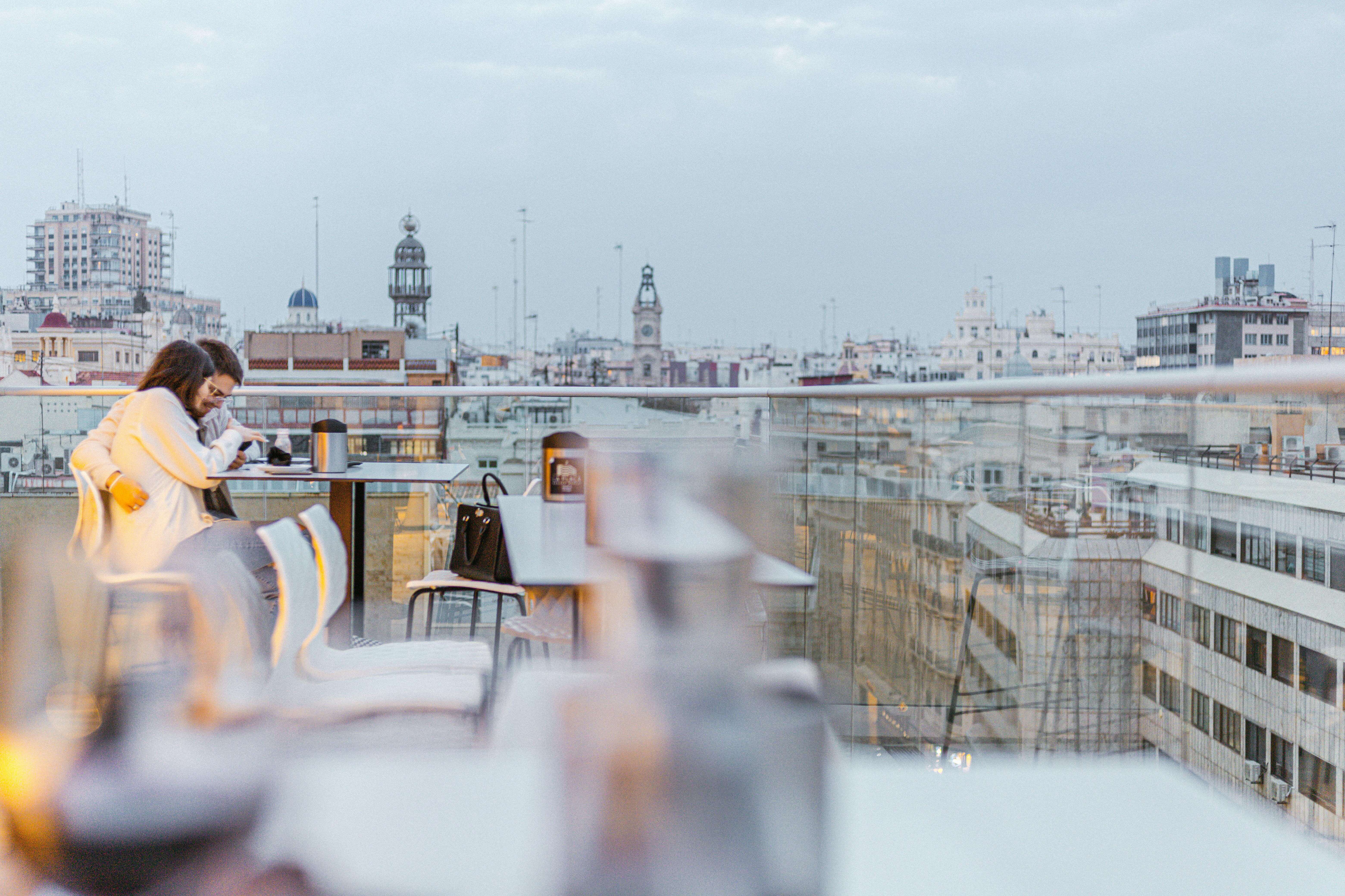 A romantic couple embraces on a rooftop terrace with a city skyline view in Spain.