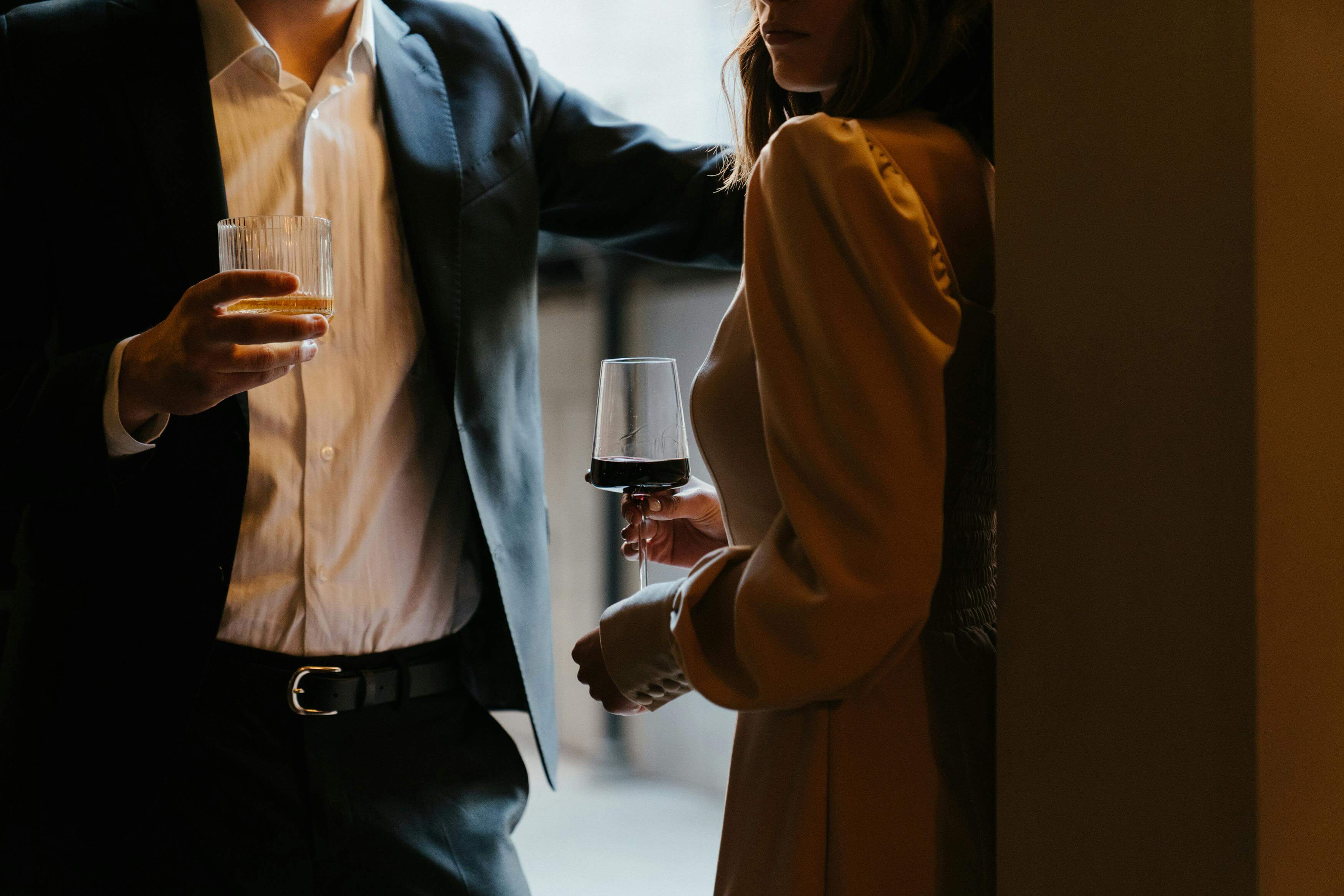 A stylishly dressed couple sharing a romantic moment with drinks at an upscale venue.