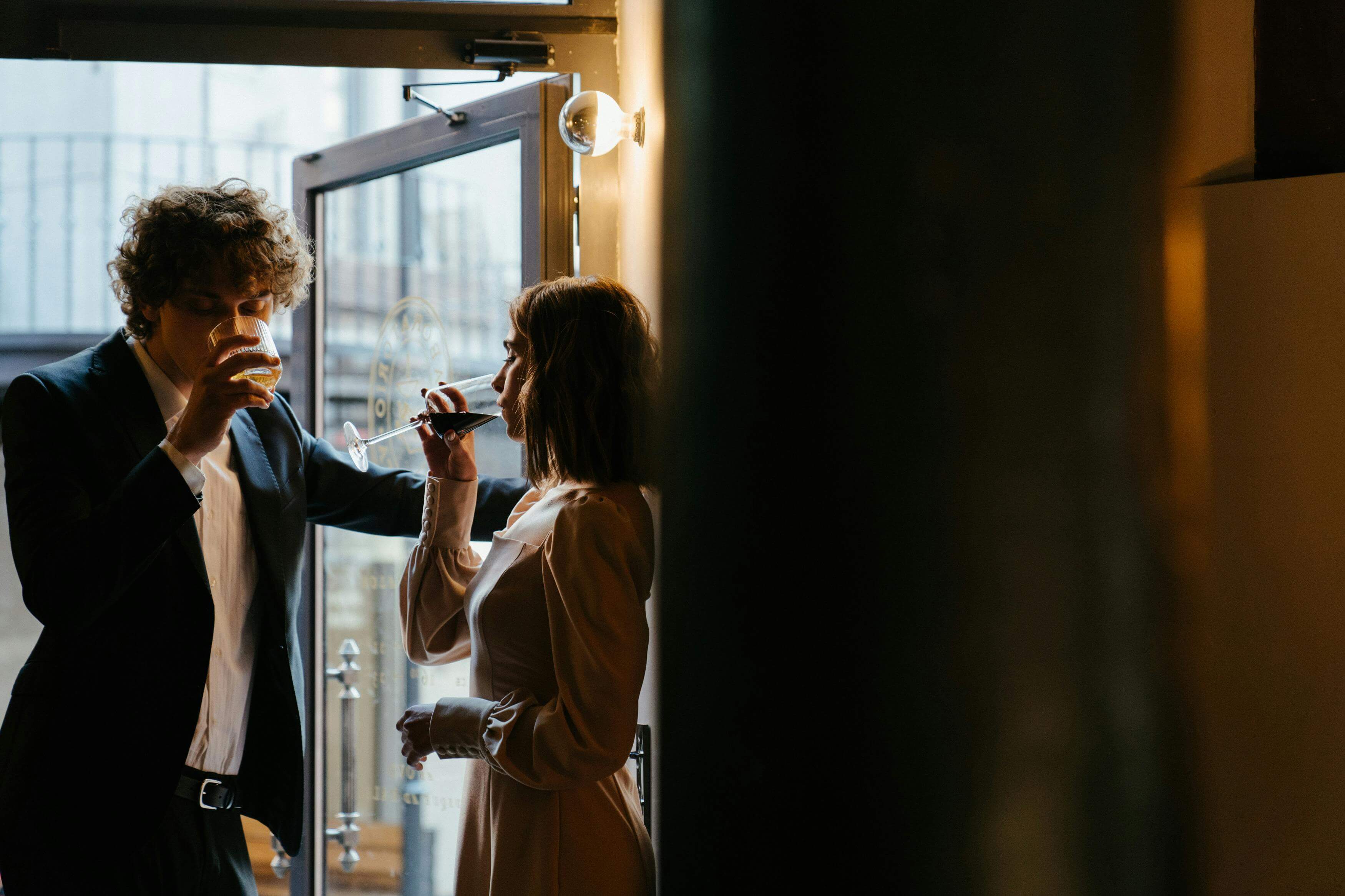 A young couple enjoying cocktails in an elegant bar setting, dressed stylishly.