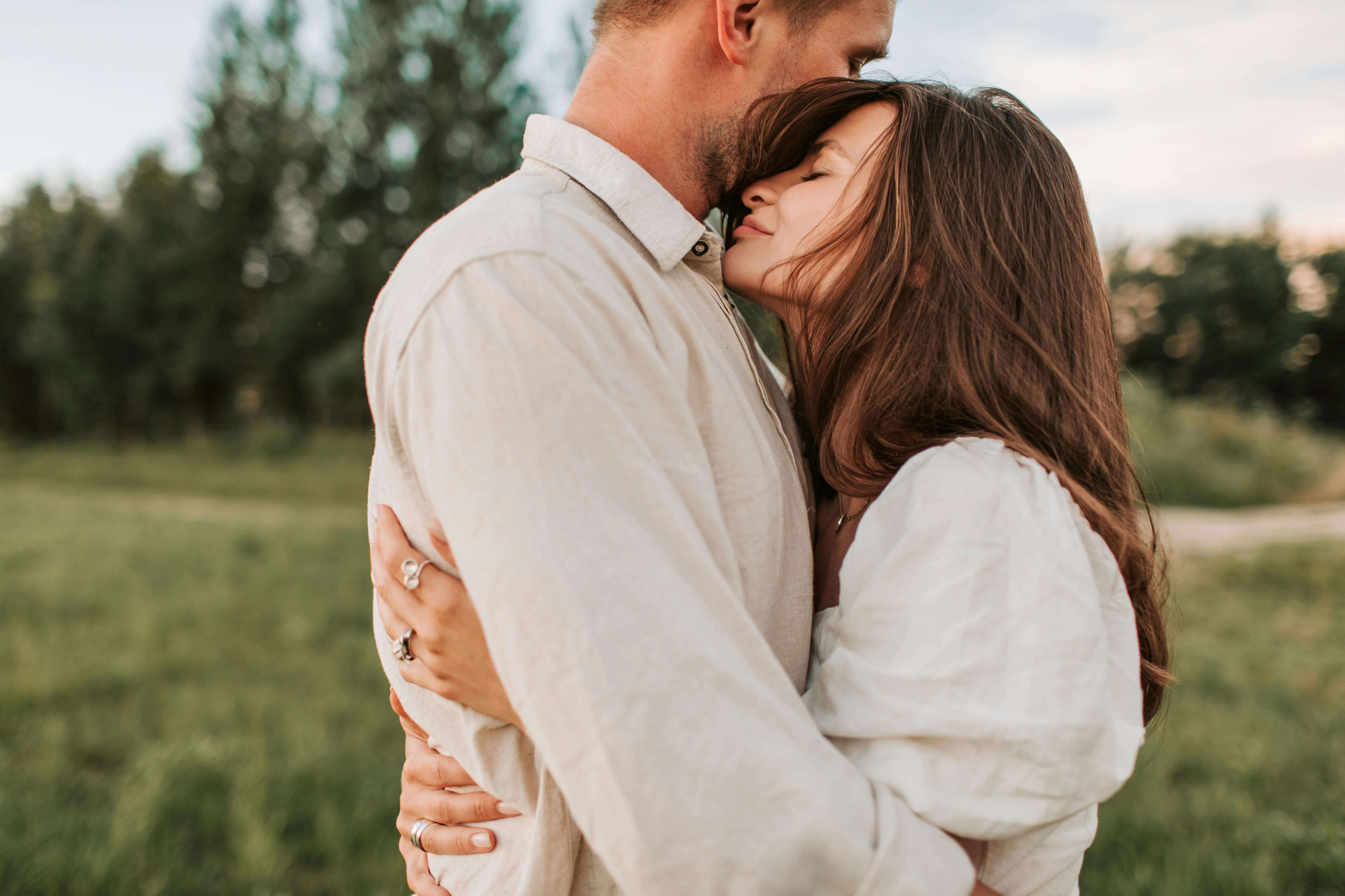 A loving couple shares an intimate embrace in a serene outdoor setting, symbolizing affection and connection.