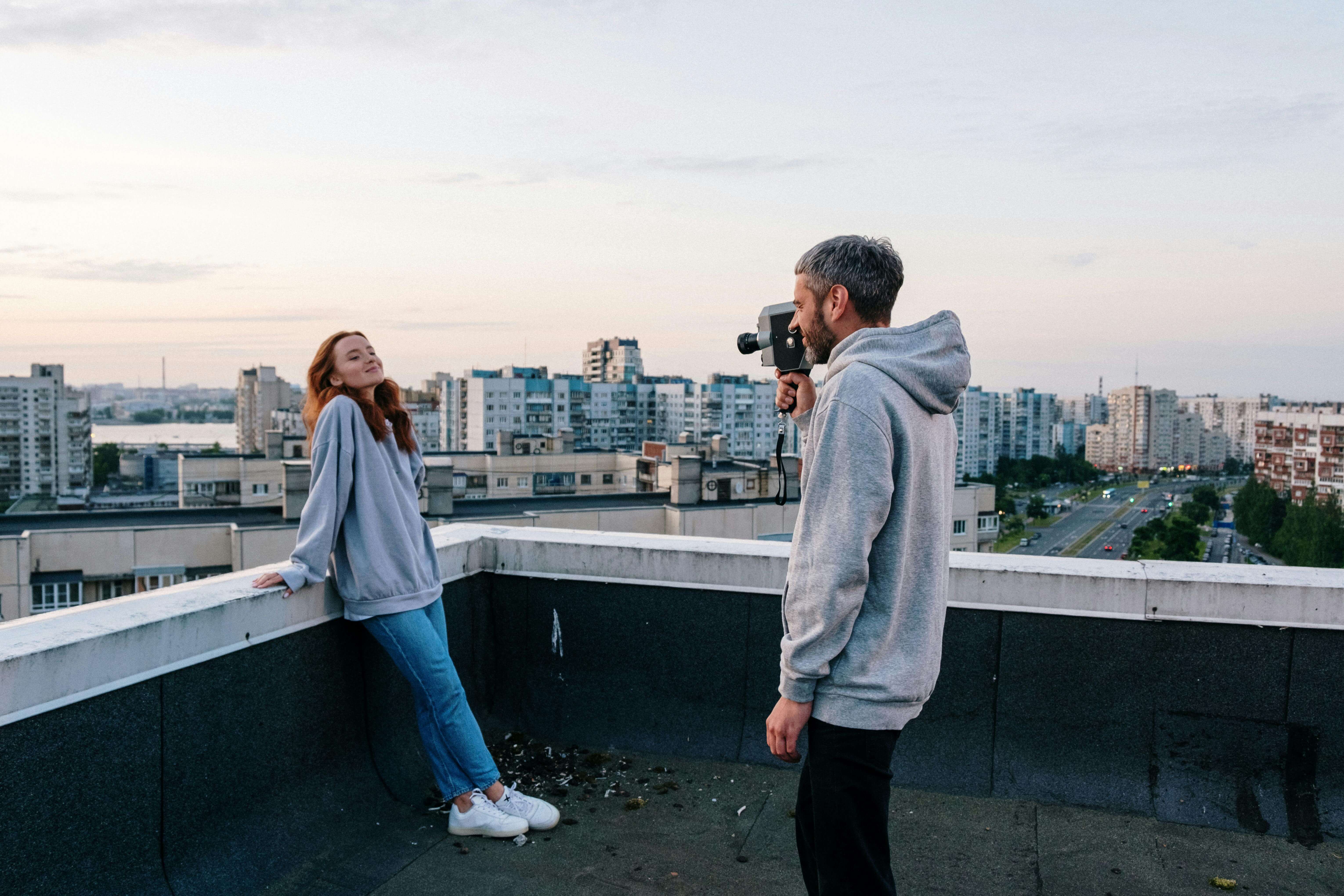 A couple enjoying a relaxed evening photo shoot on a rooftop, capturing candid urban moments.
