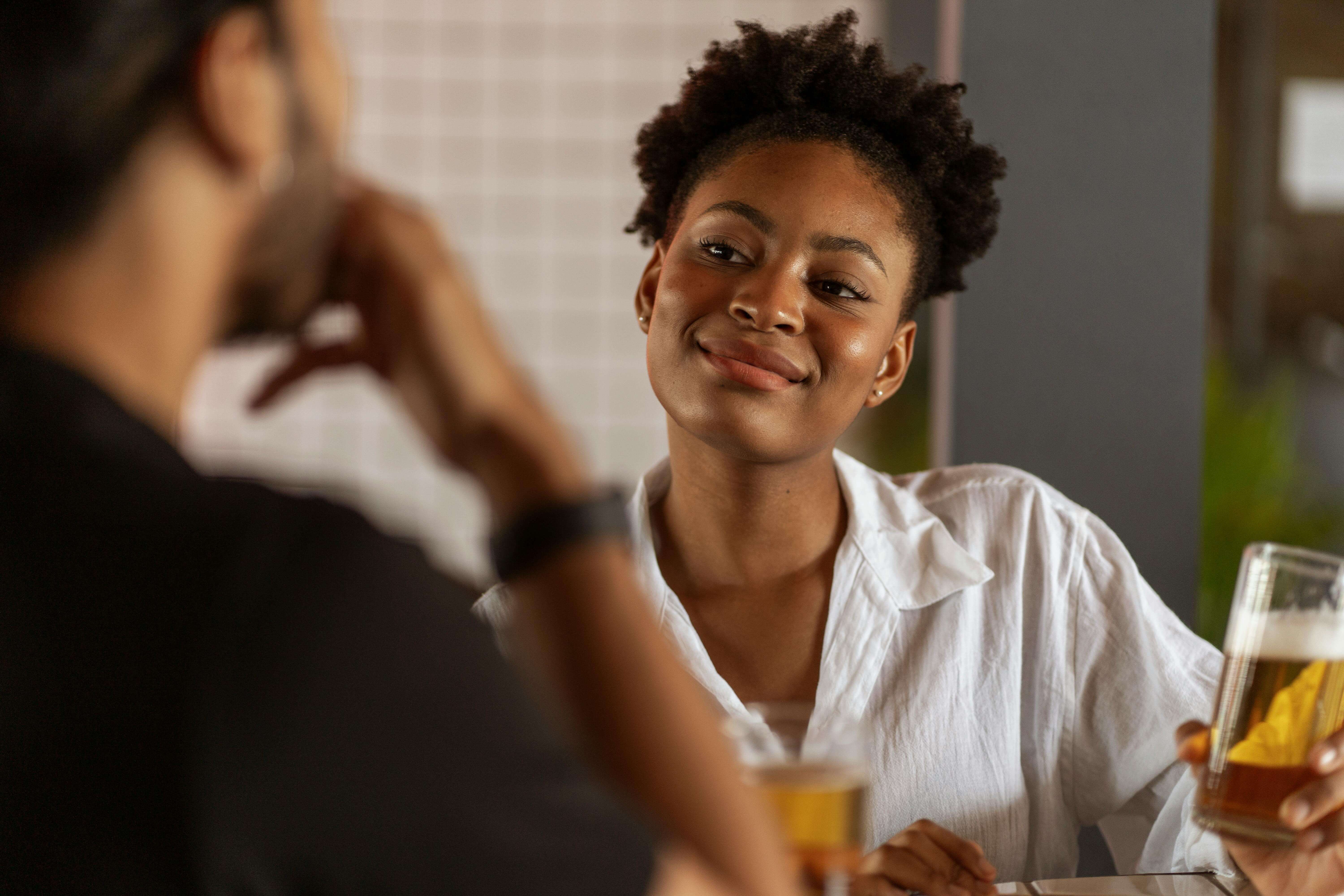 A young couple enjoying beer together, fostering connection and laughter indoors.