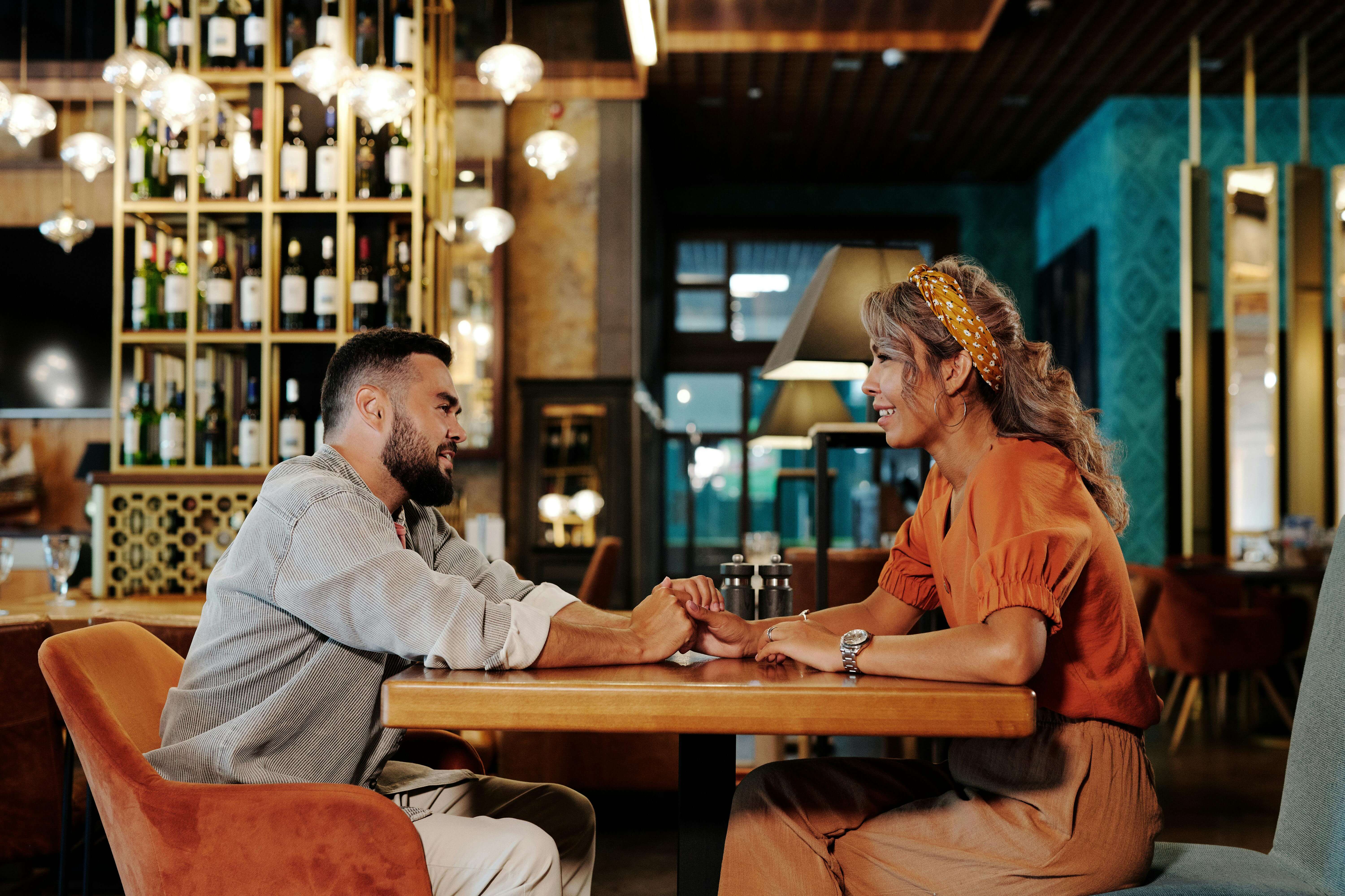 A couple enjoying a romantic date, holding hands in a stylish cafÃ© setting.