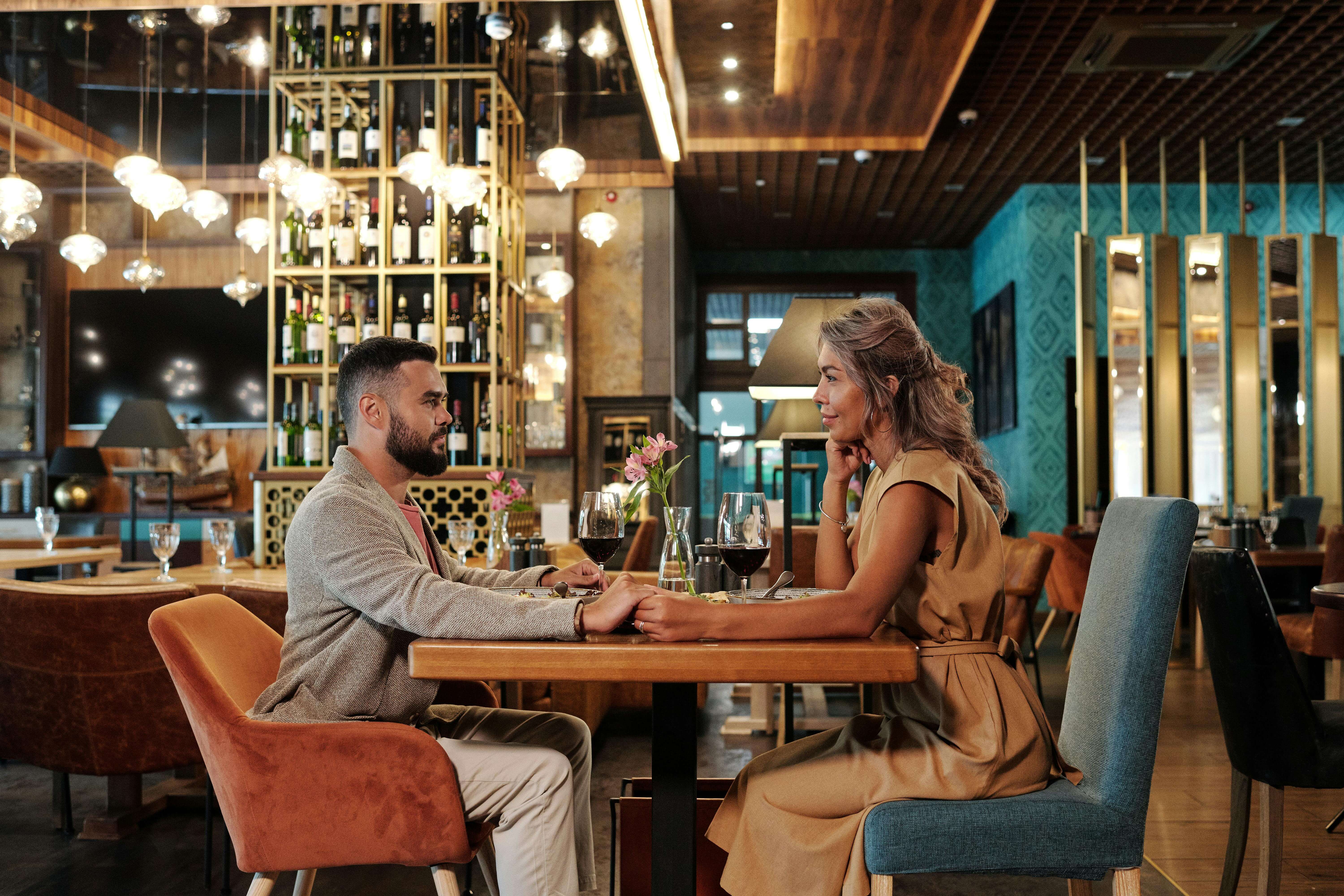 Couple enjoying a romantic dinner with wine in an elegant restaurant setting, creating a warm atmosphere.
