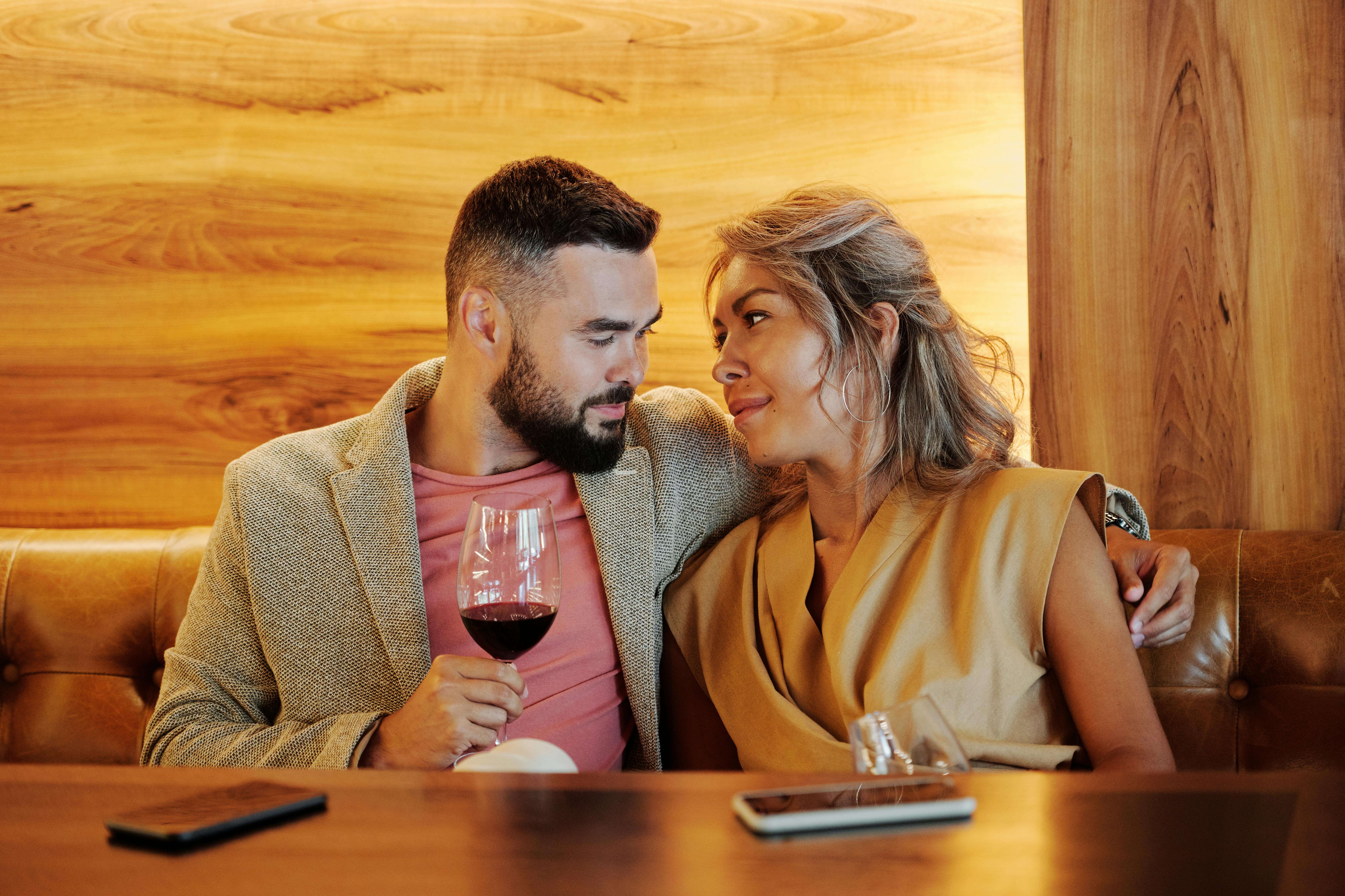A loving couple sharing a romantic moment with red wine in a stylish restaurant.