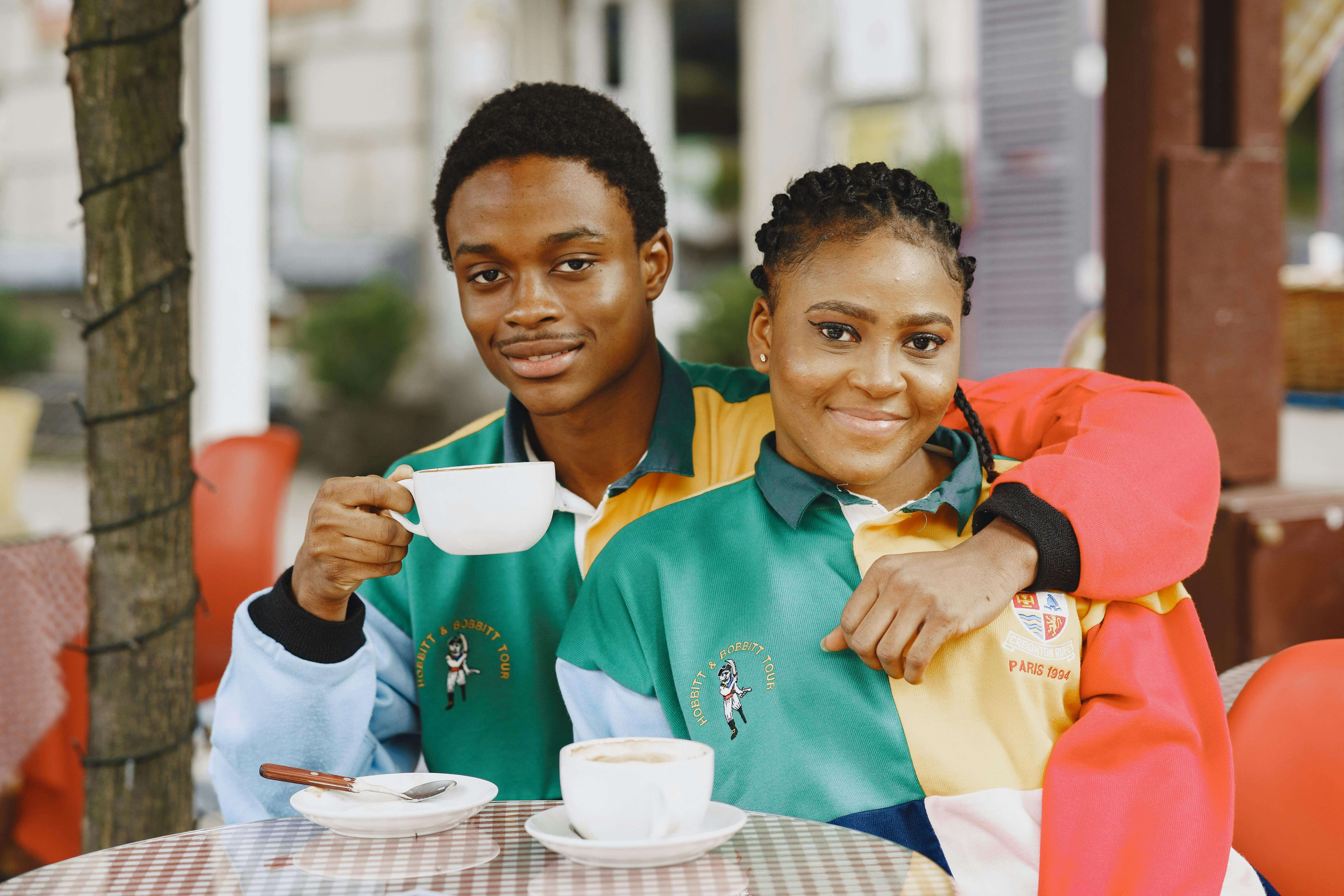 Smiling couple enjoys coffee at outdoor cafe, creating a warm romantic moment.