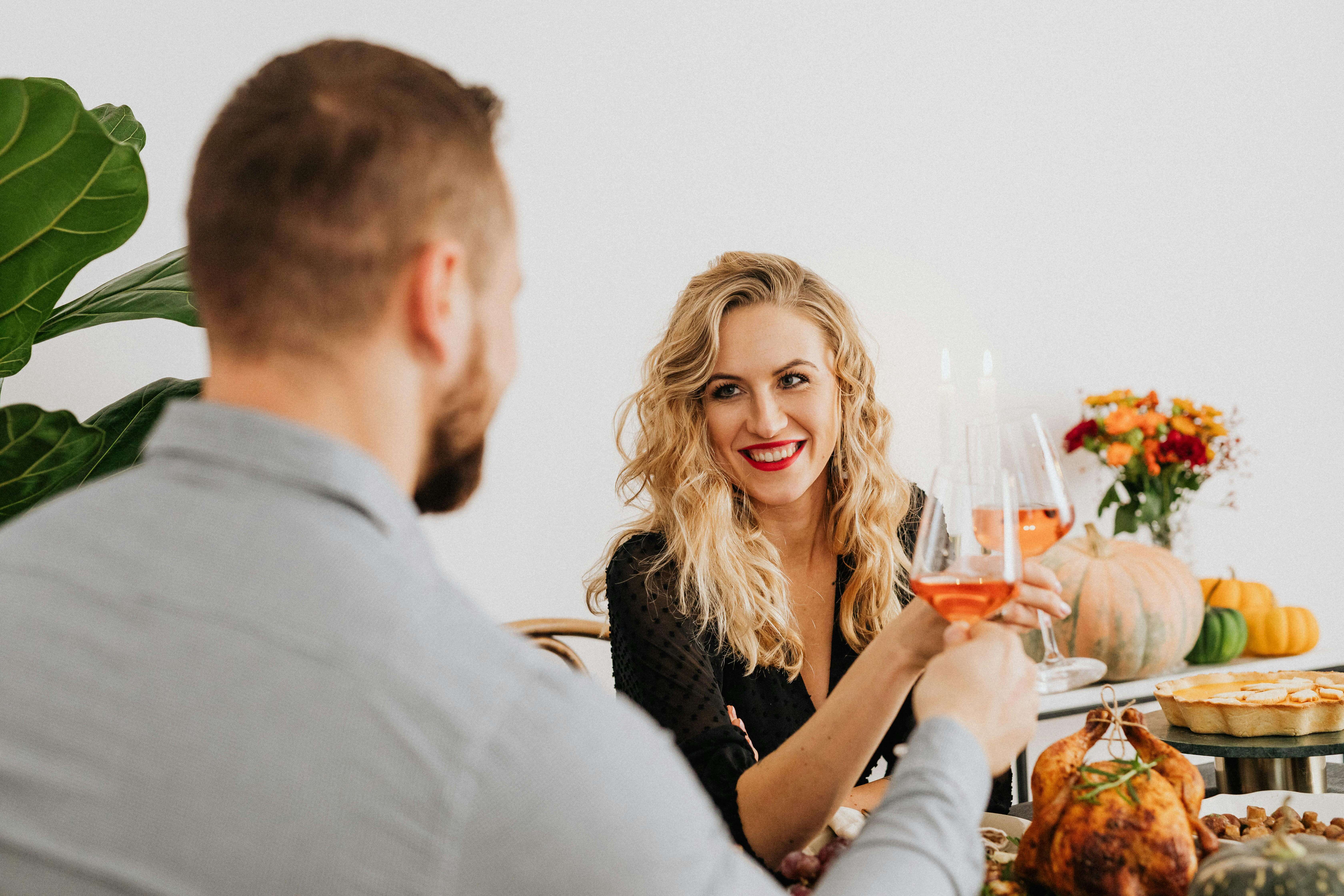 A couple enjoys a romantic dinner indoors, toasting with wine and sharing a joyful moment.