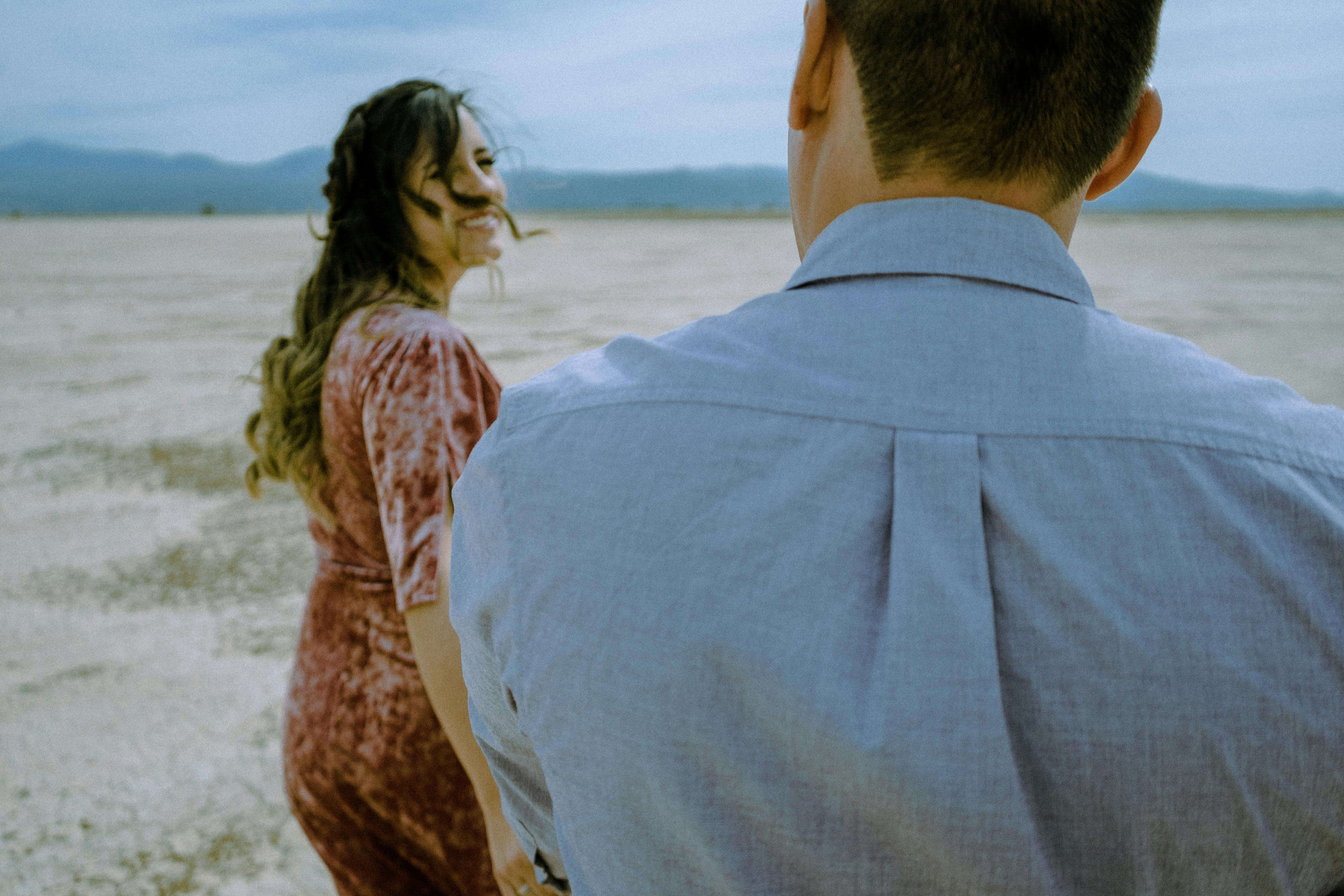 Joyful couple strolling in a vast desert setting, capturing a moment of happiness and love.