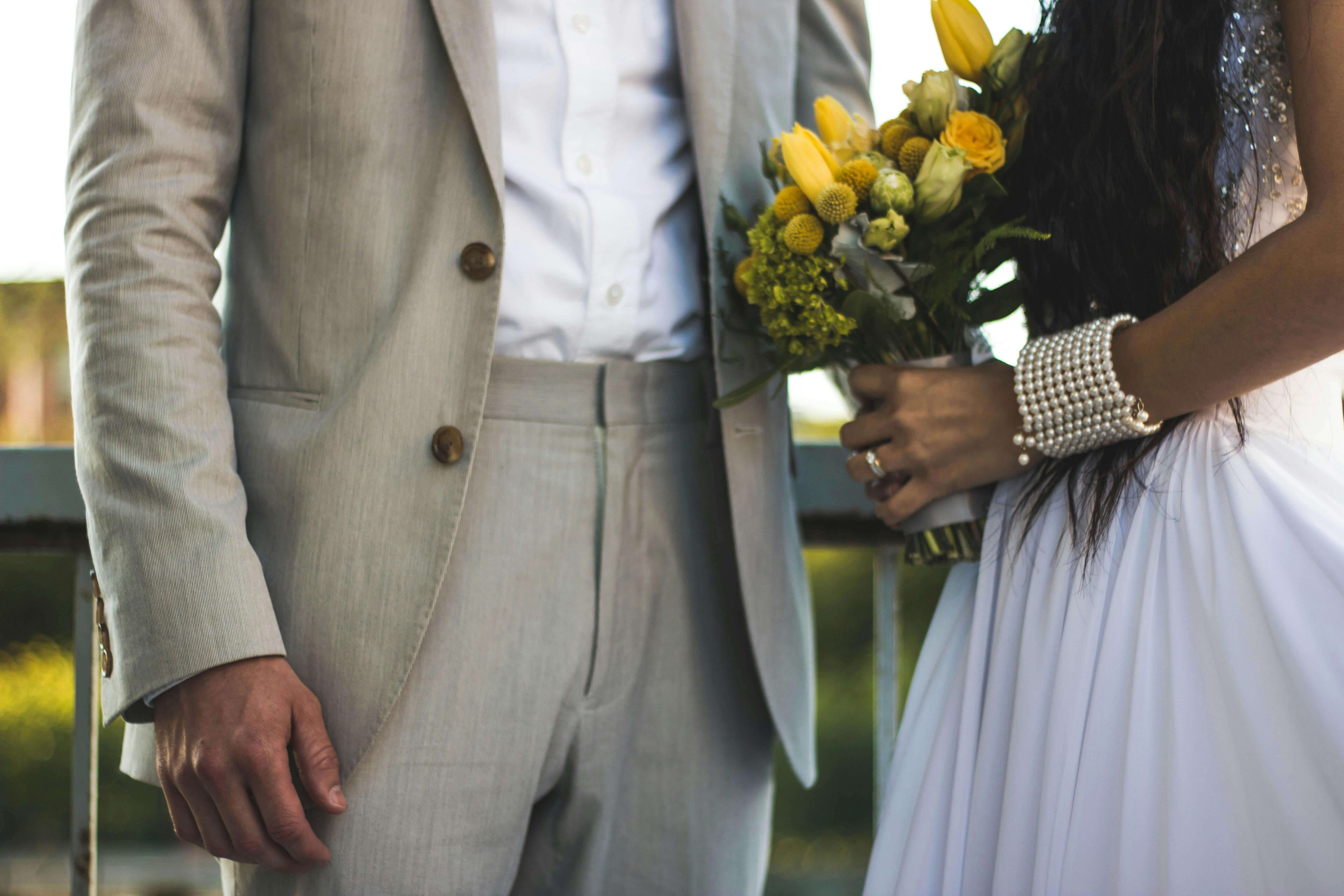 Close-up of a bride and groom with a yellow floral bouquet, showcasing elegance and love.