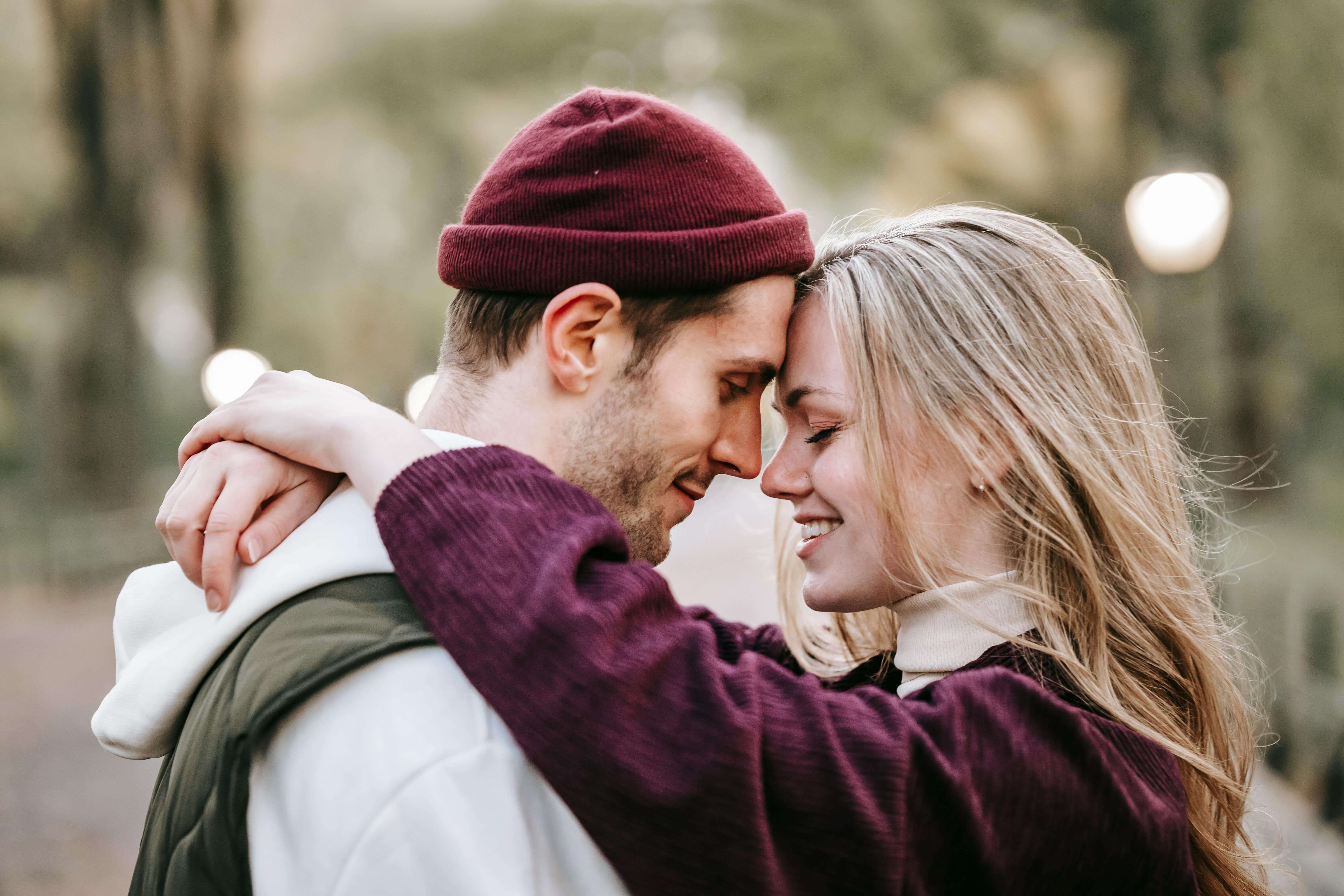 Young couple enjoying a tender moment in a scenic park during fall.