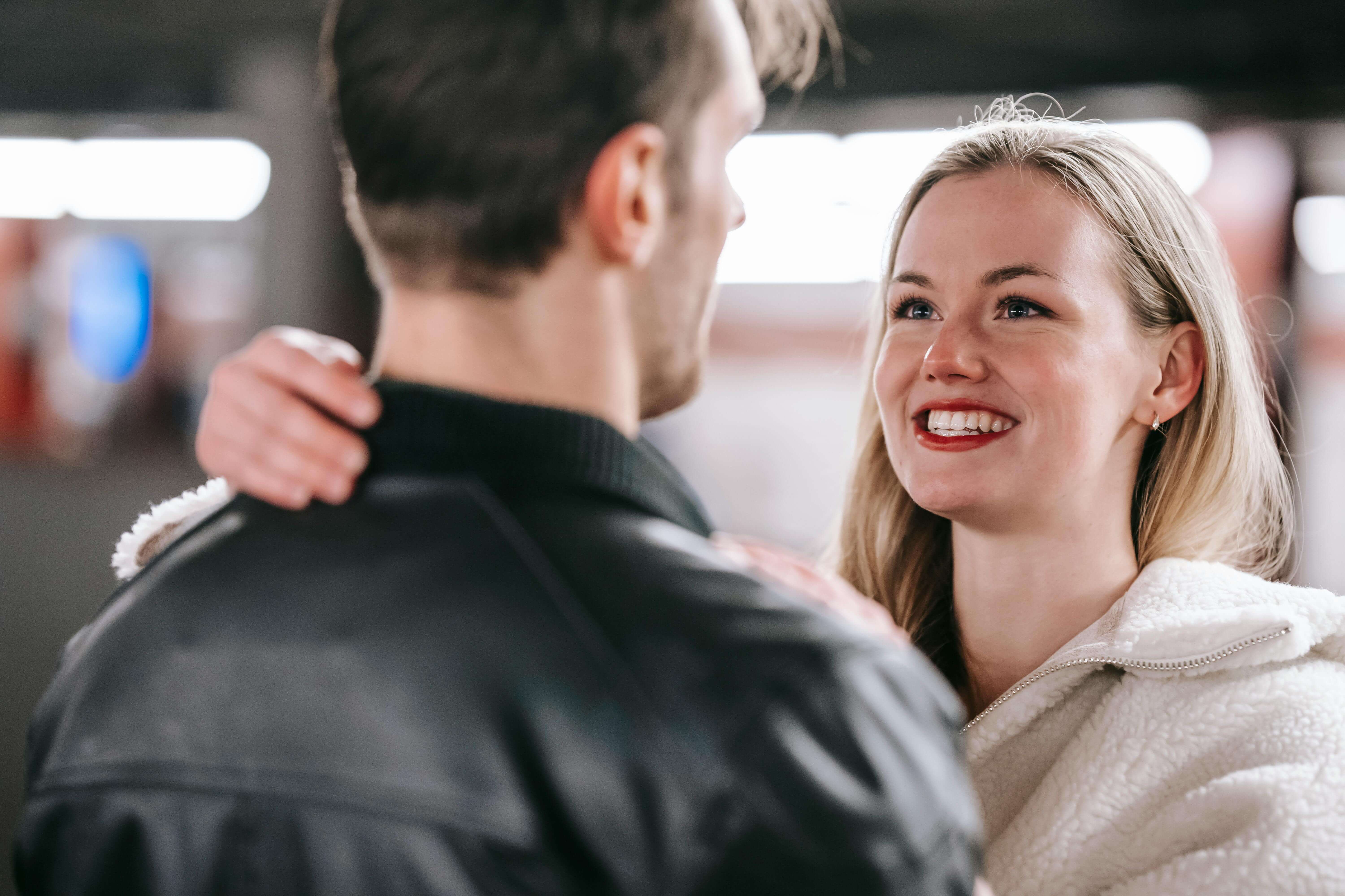 Crop cheerful couple hugging tenderly while toothy smiling and looking at each other