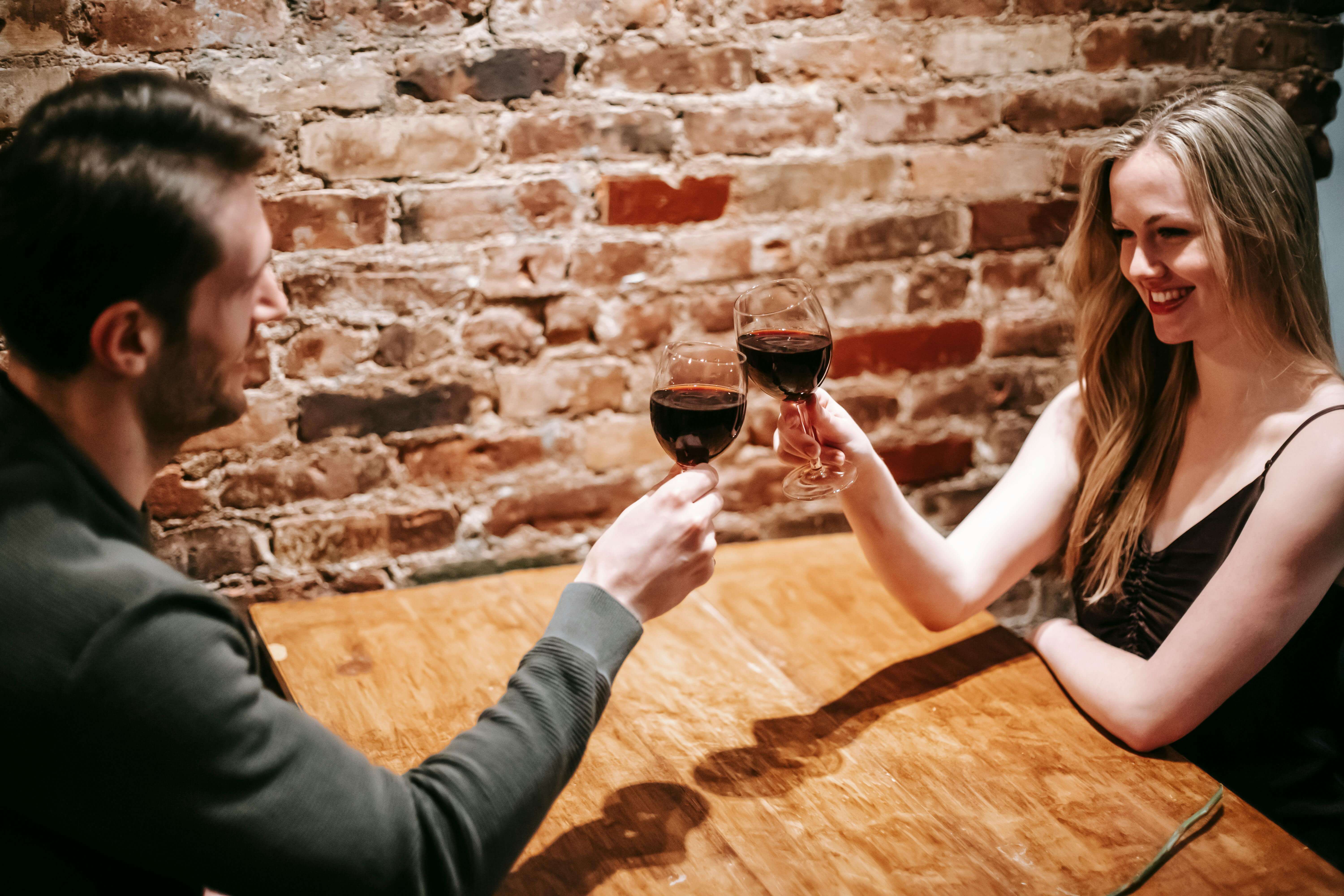 Couple enjoying a romantic evening, toasting with red wine in a cozy restaurant.