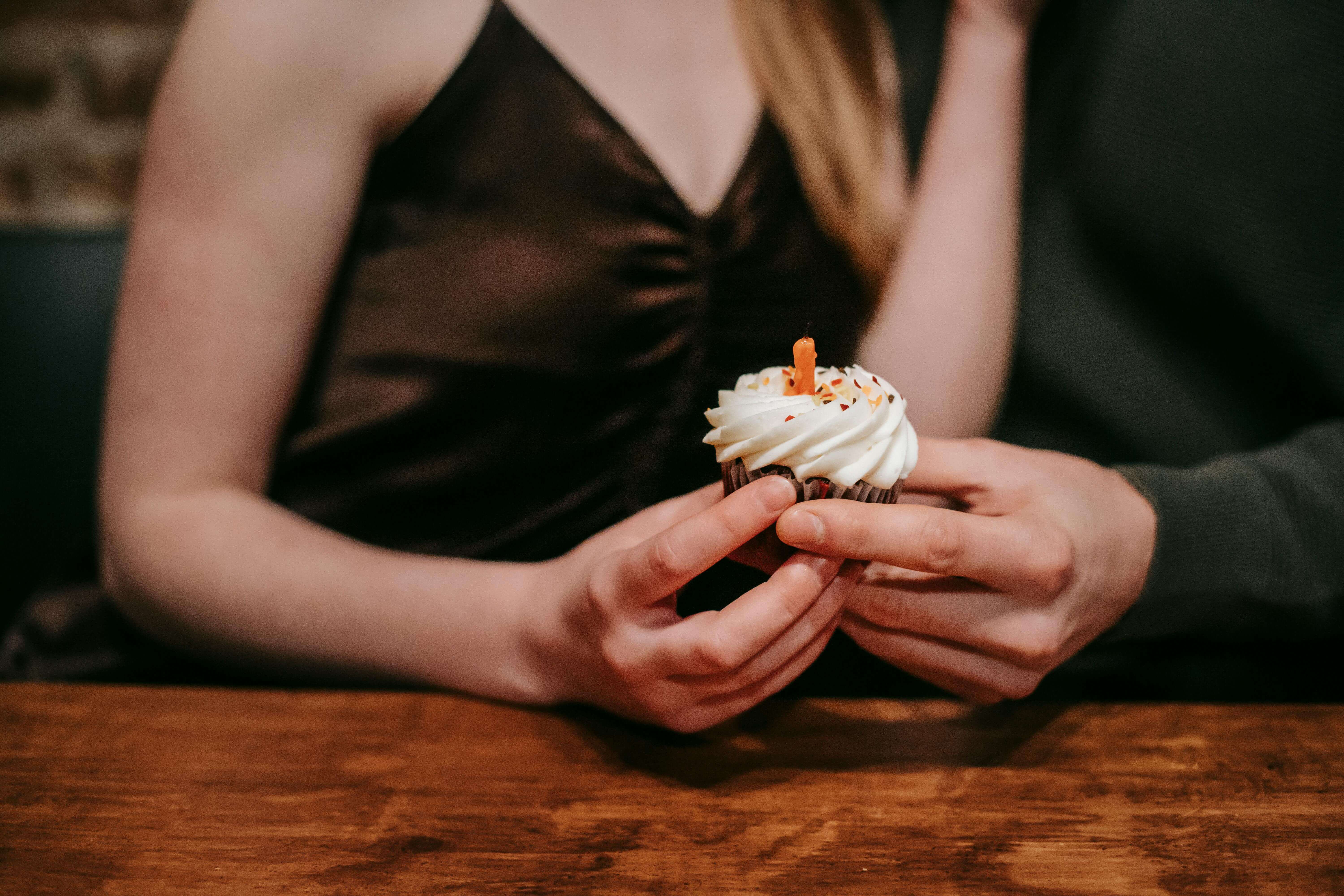 A couple shares a sweet moment holding a cupcake with a candle. Perfect for celebrations.