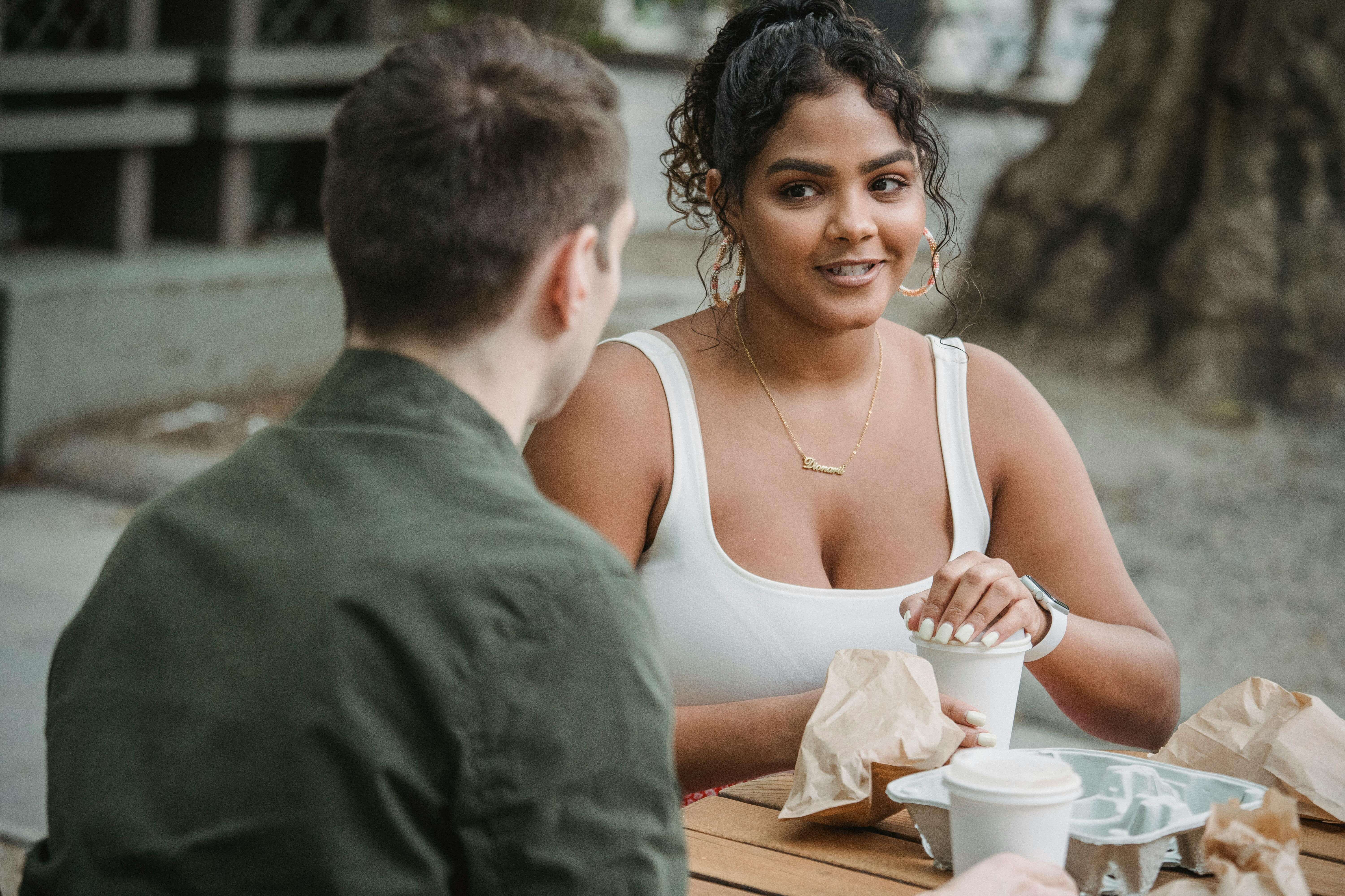 A young couple enjoying a coffee date at an outdoor cafÃÂ©, engaging in lively conversation.