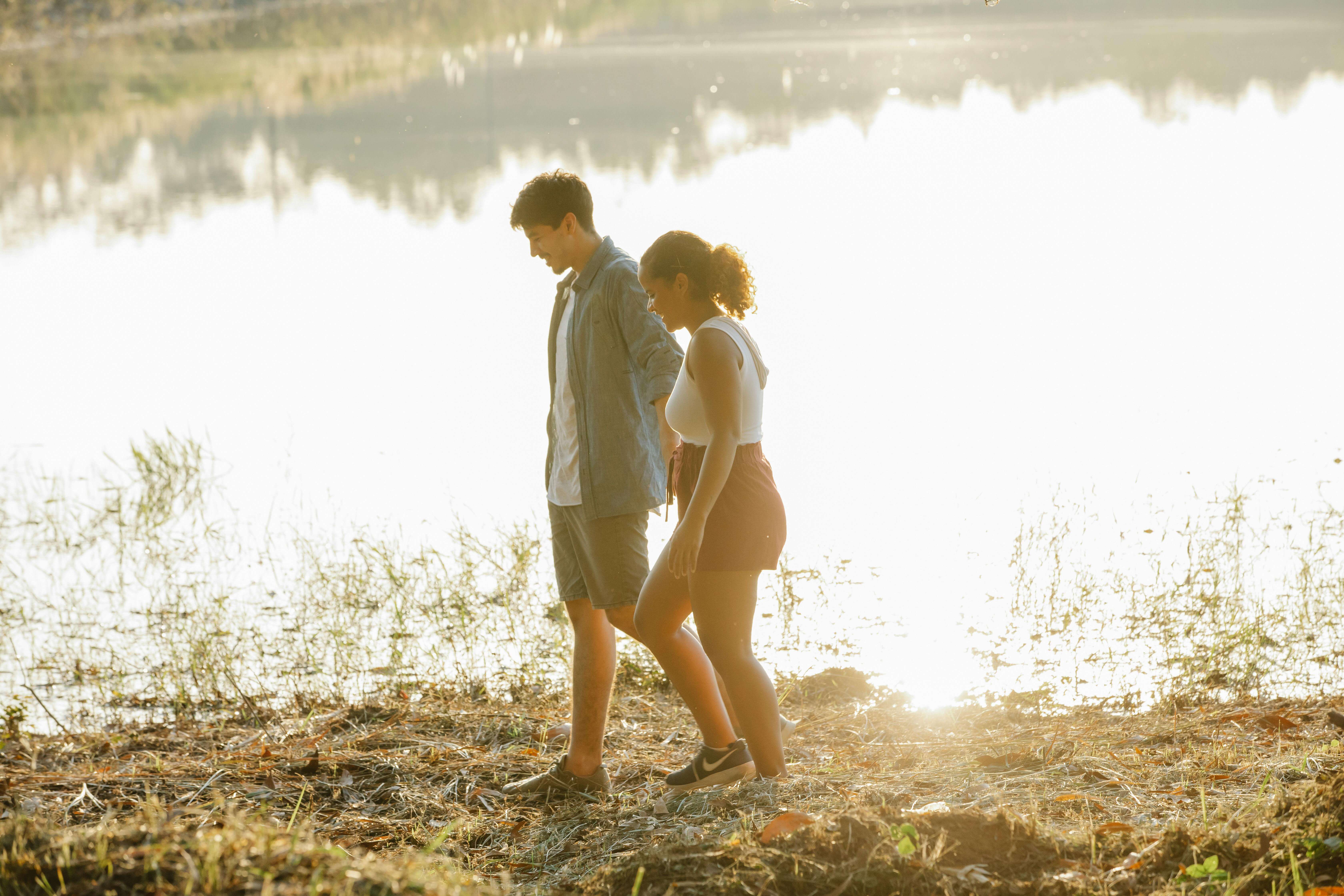 Young couple enjoying a peaceful walk by the lake, capturing love and tranquility.