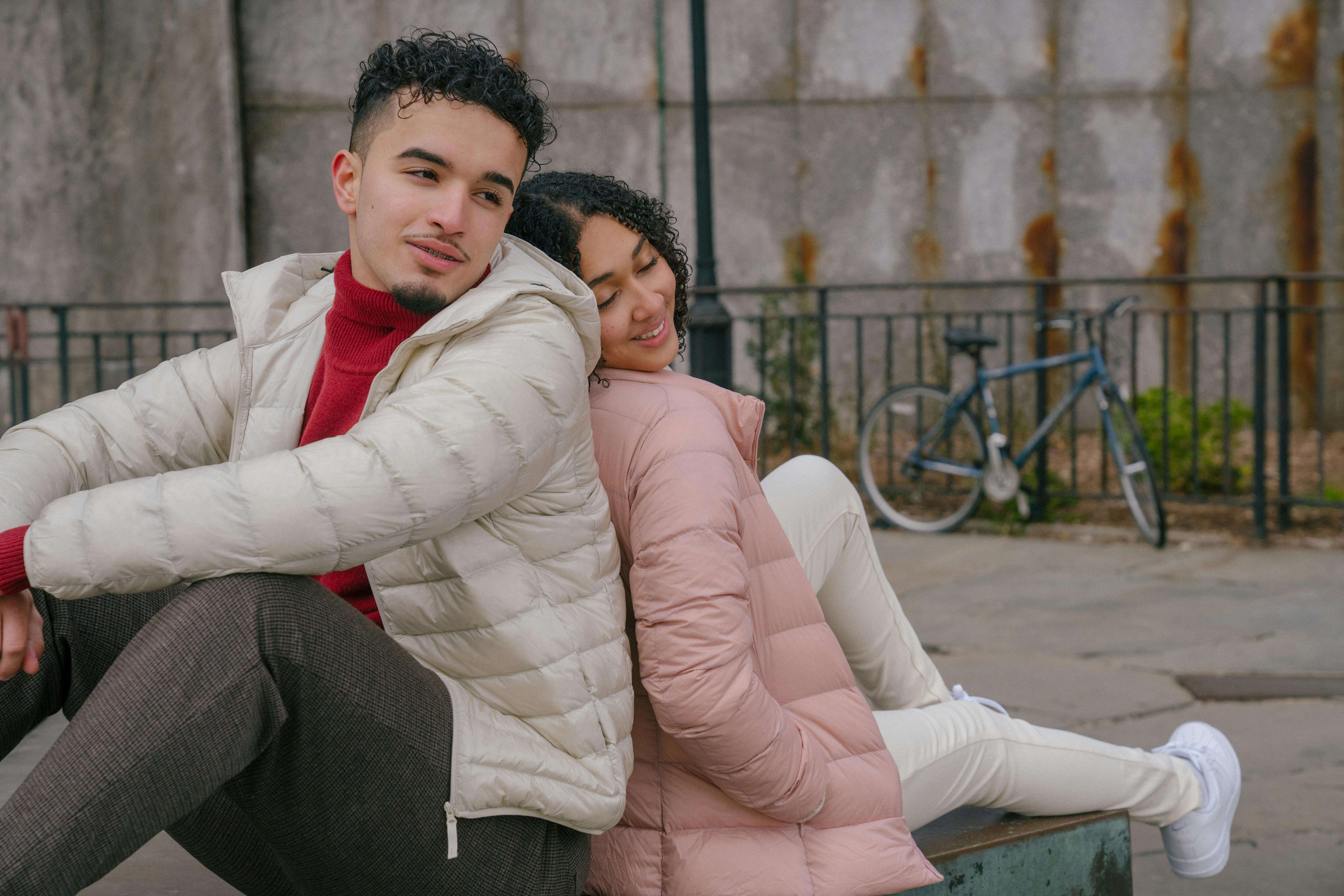 Smiling young couple sitting together outdoors, exuding joy and connection.