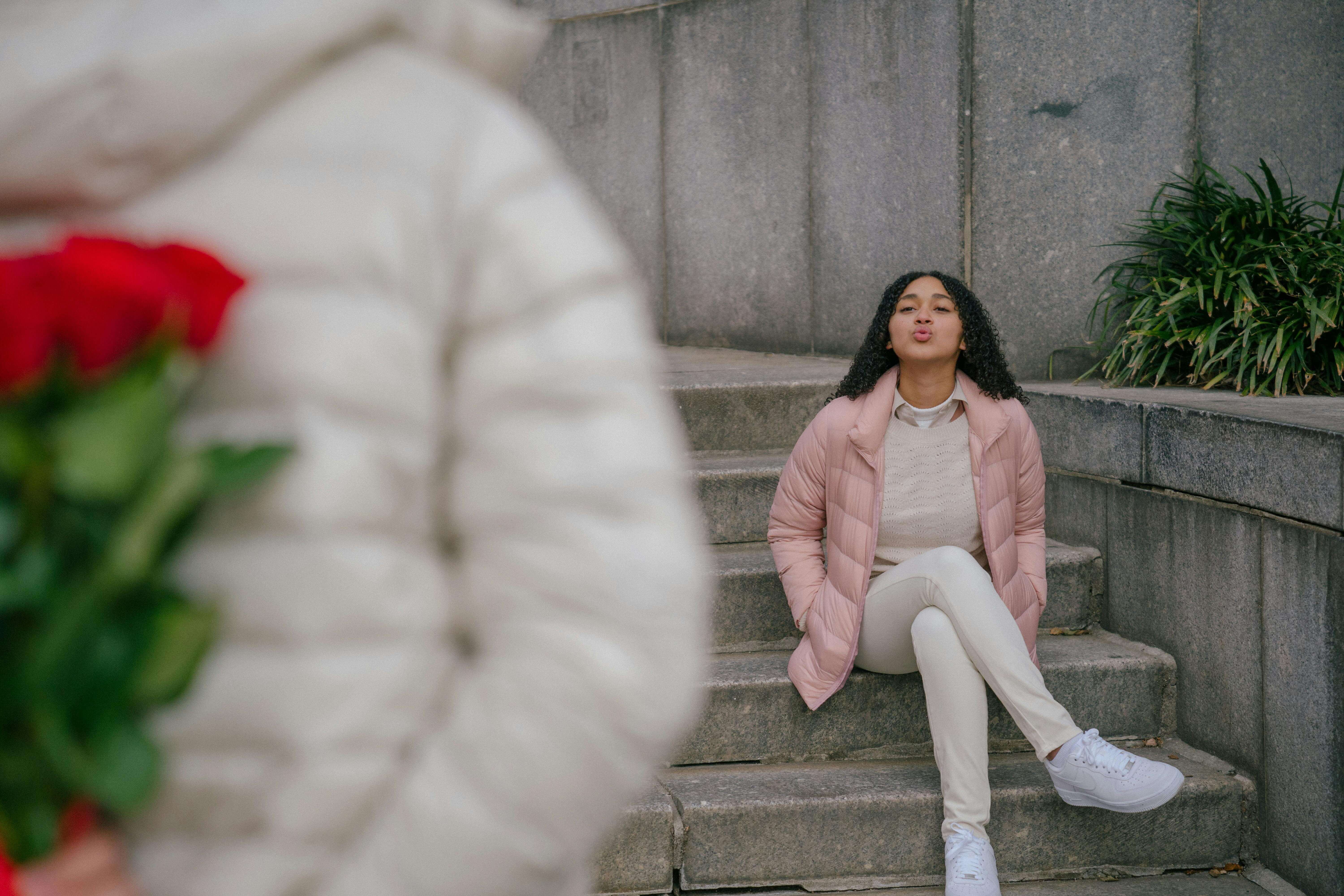 A romantic gesture unfolds as a woman receives a bouquet of roses on a staircase, capturing a moment of surprise and love.