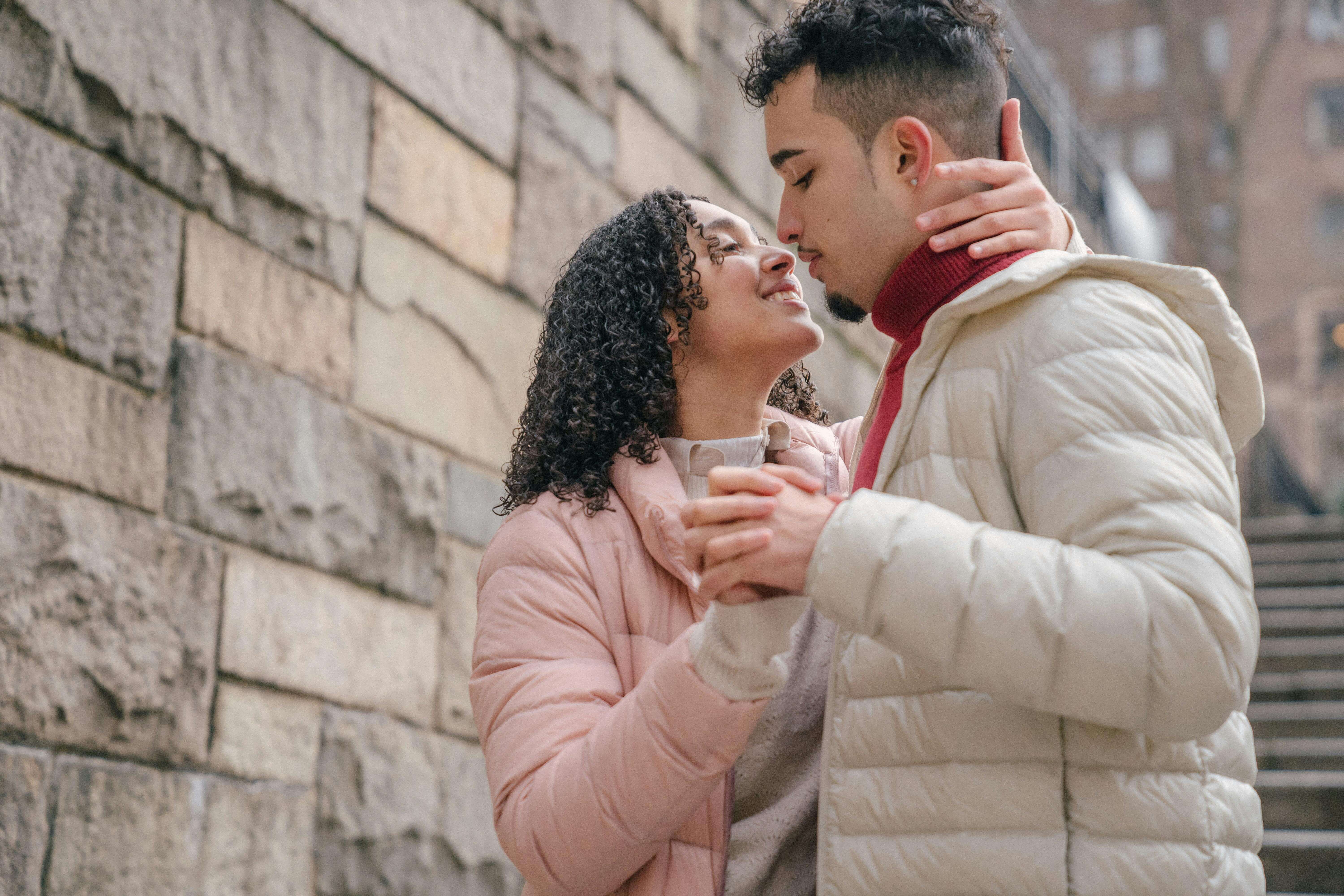Young couple sharing a tender moment on a stone stairway during winter.