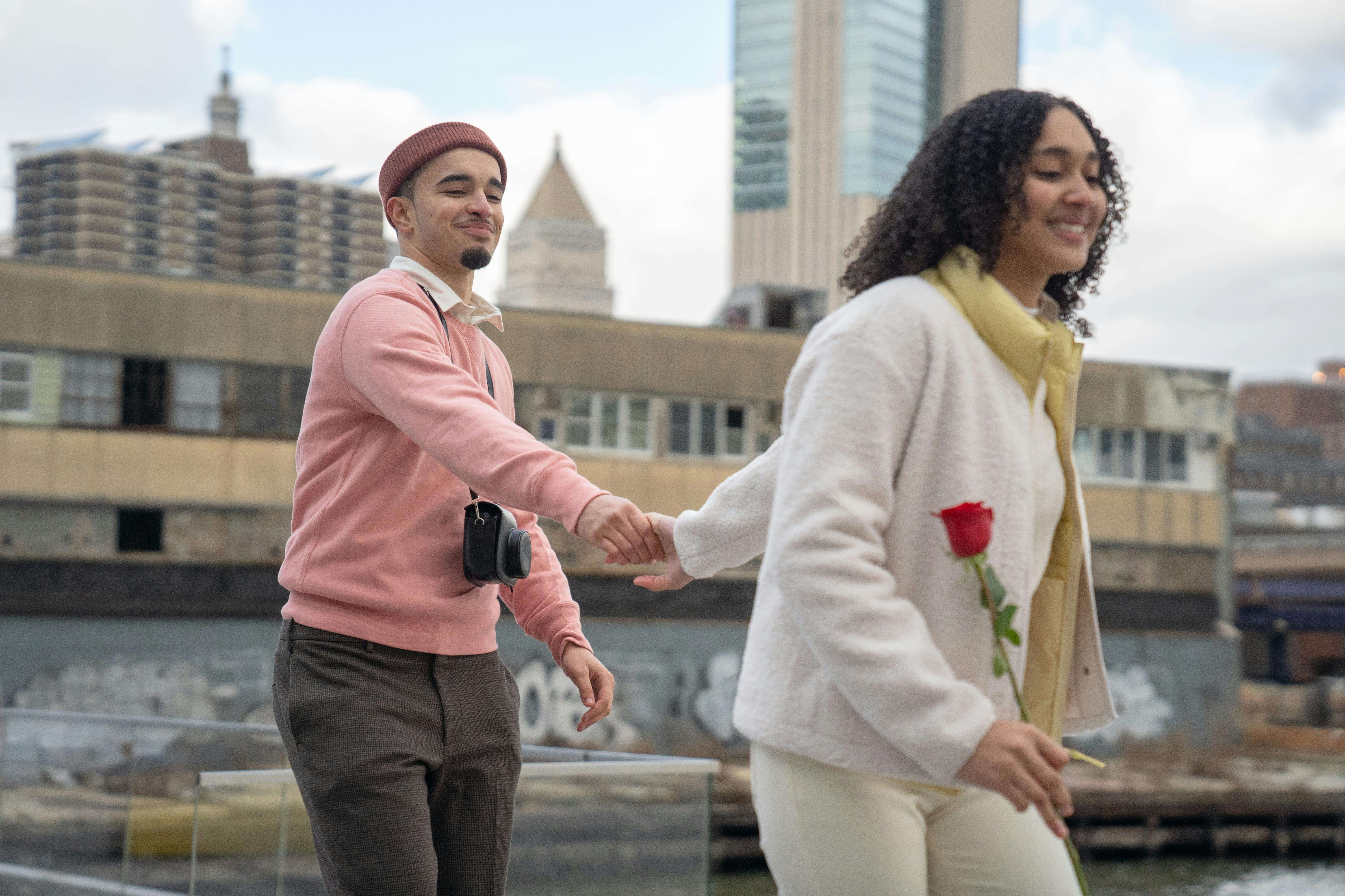 Happy couple holding hands with a rose on a city stroll, capturing romantic moments.