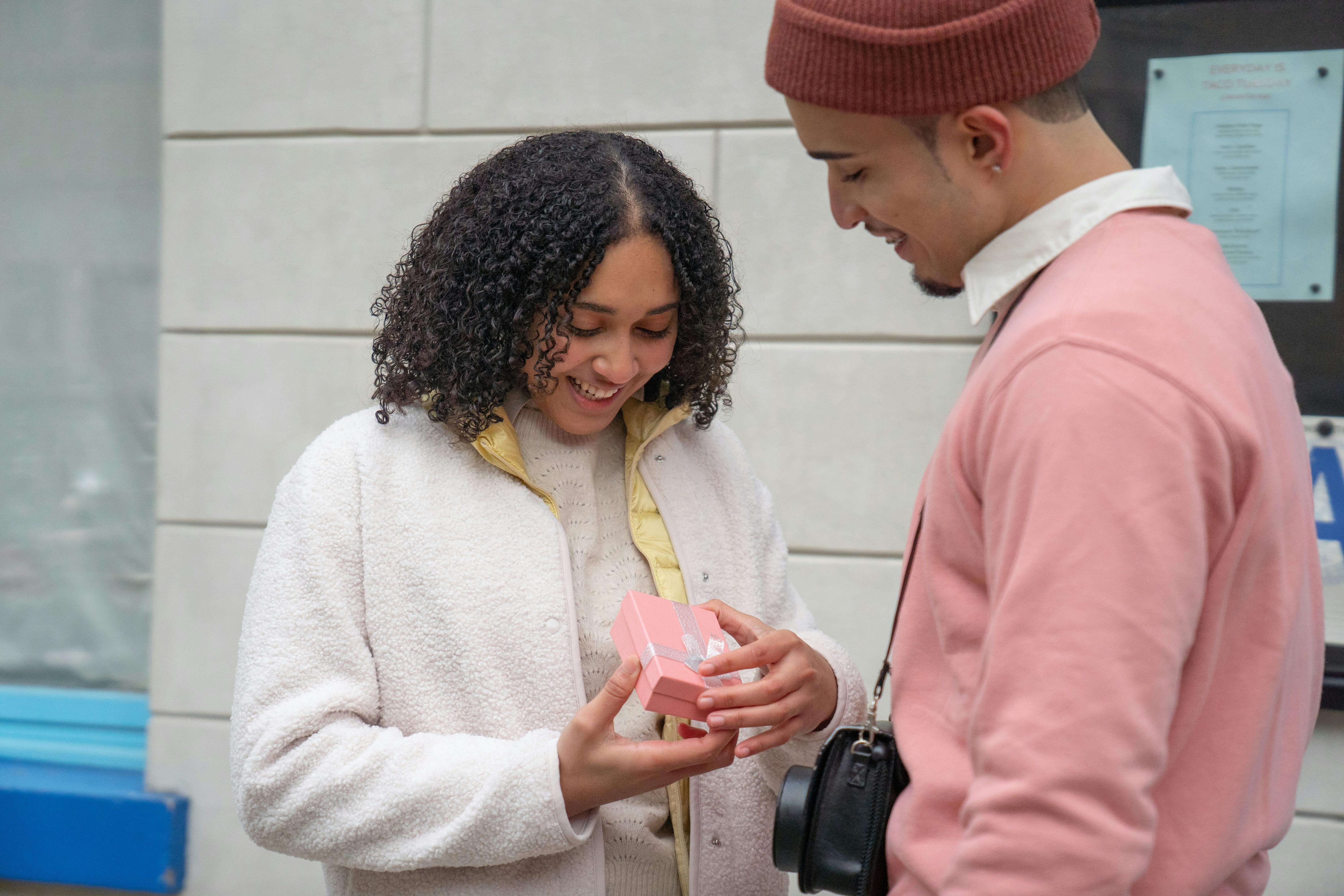 A couple joyfully exchanging a gift on a city street, symbolizing love and happiness.