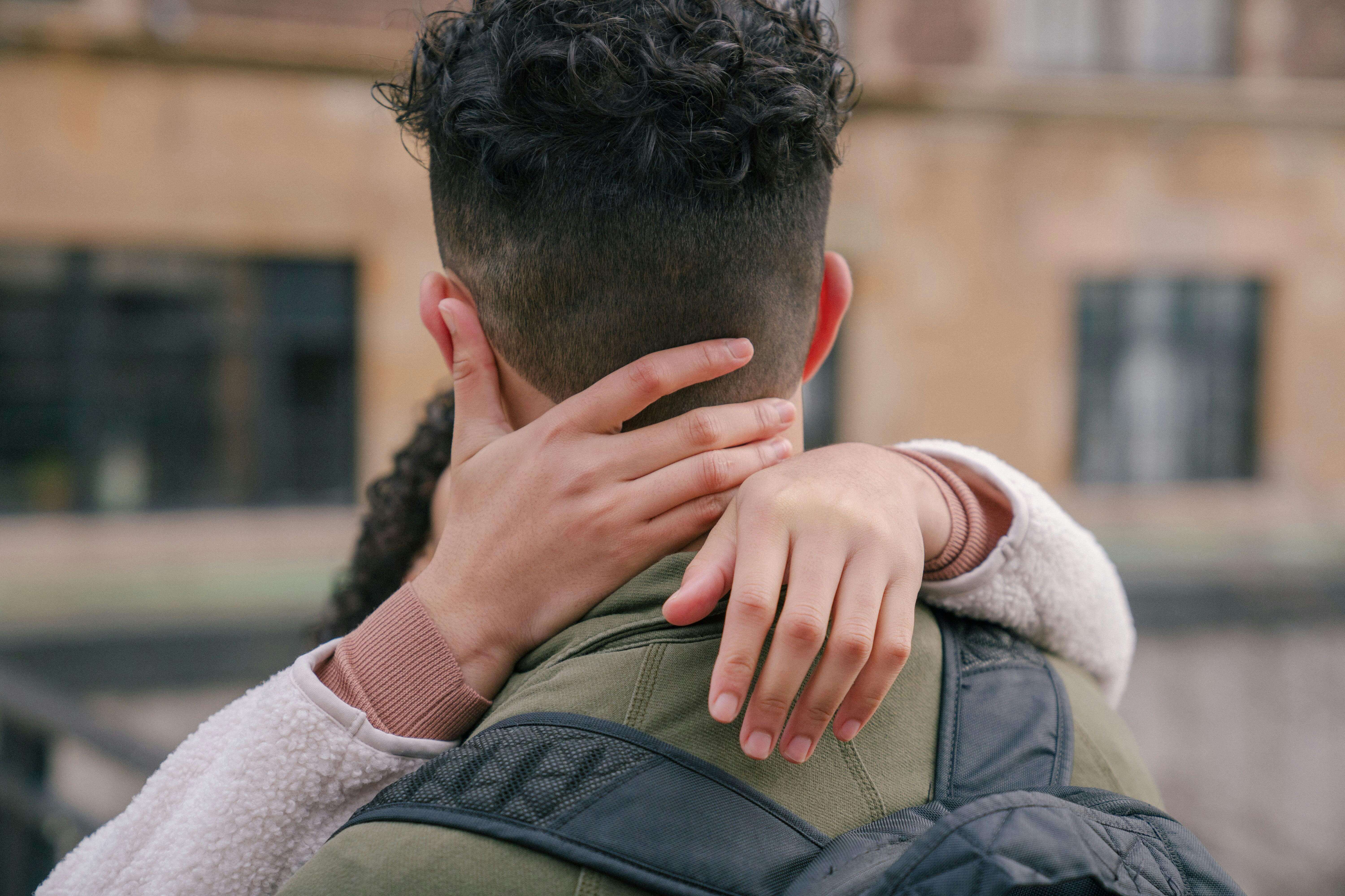 A couple embracing outdoors with a focus on their affectionate gesture.