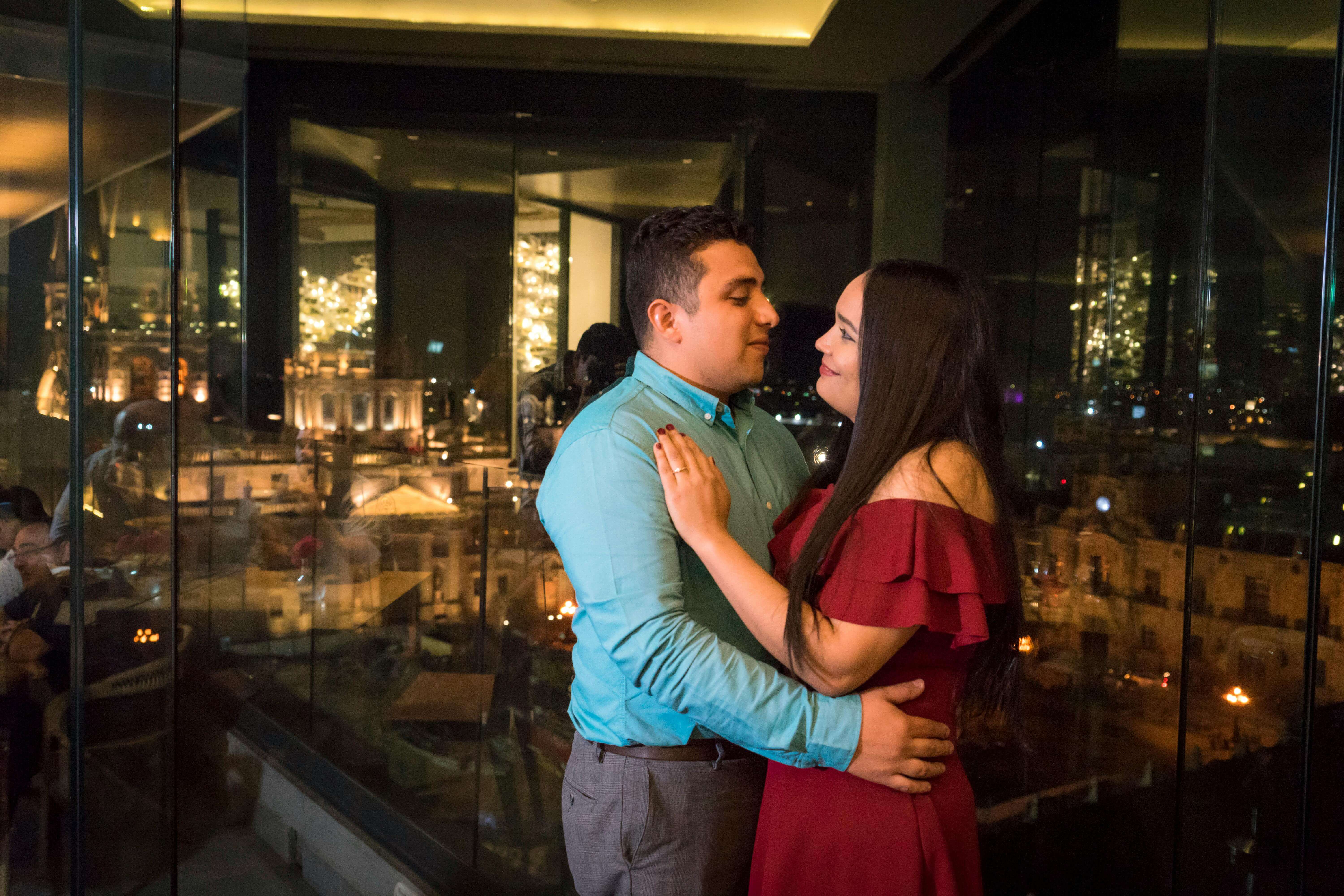 A loving couple sharing a romantic moment with a nighttime city backdrop.