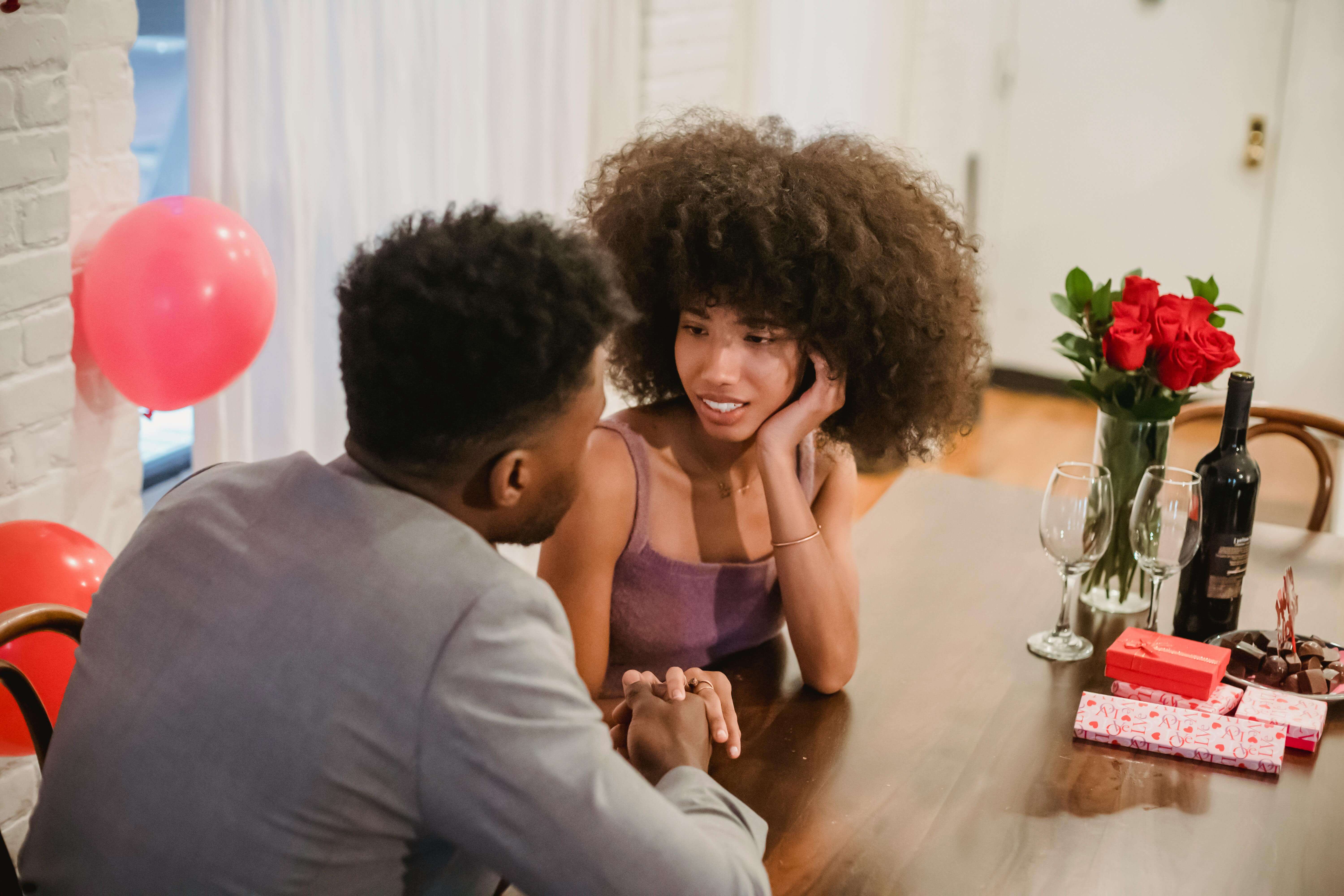 A couple sharing a romantic moment at a beautifully decorated dinner table with wine and gifts.