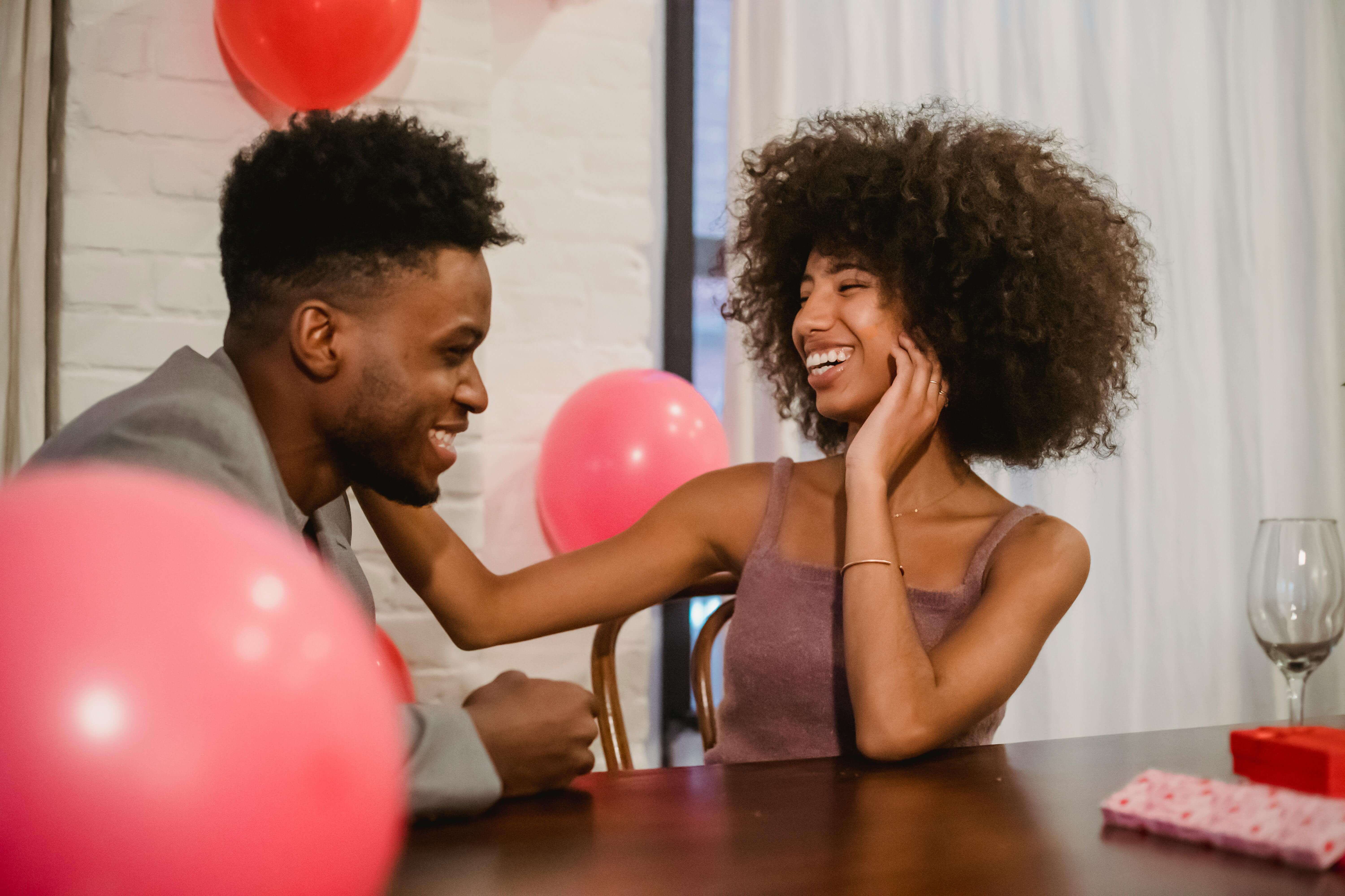 Happy couple enjoying a romantic indoor date with balloons, sharing laughs and love.