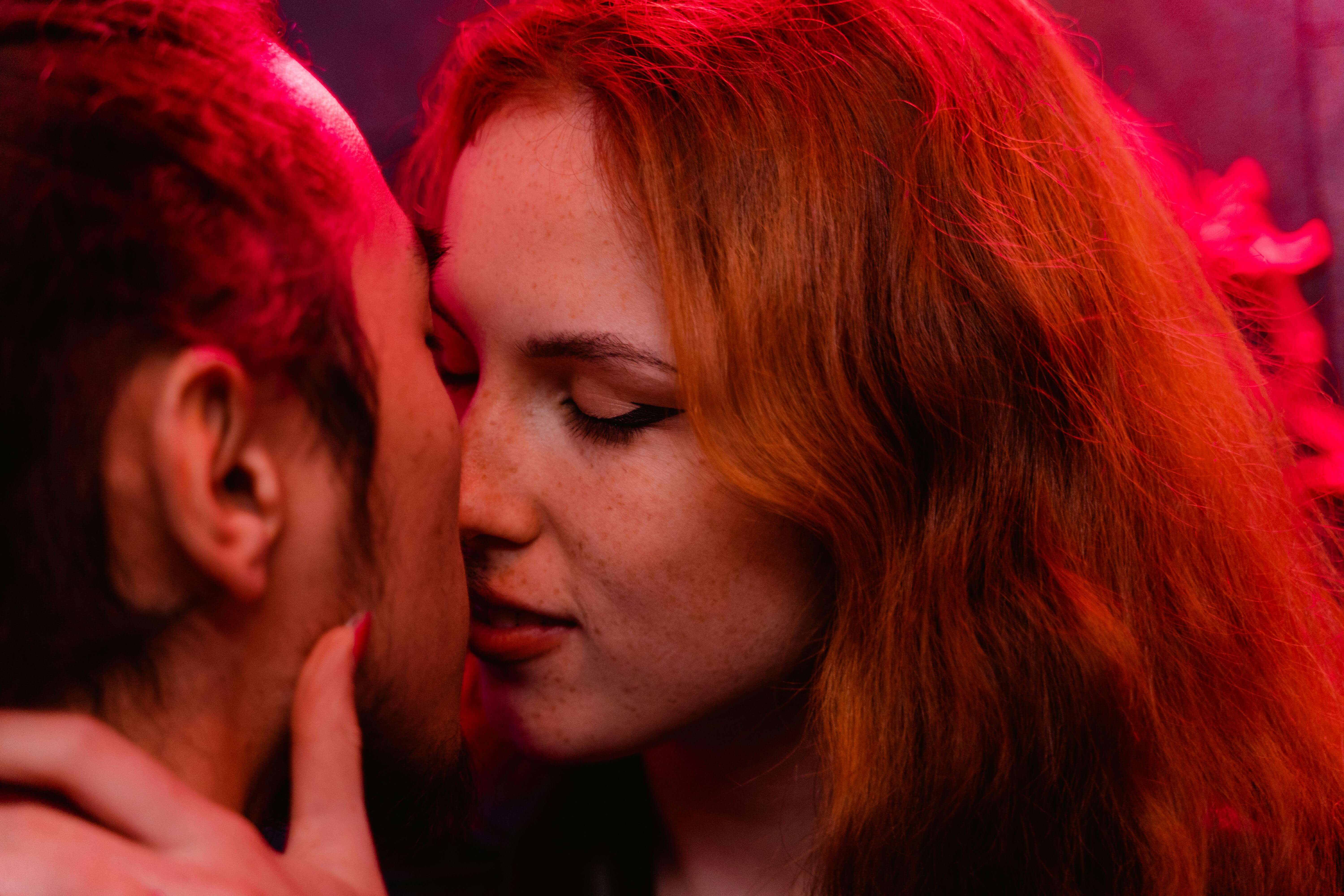 Intimate moment captured as a couple shares a kiss under club lights.