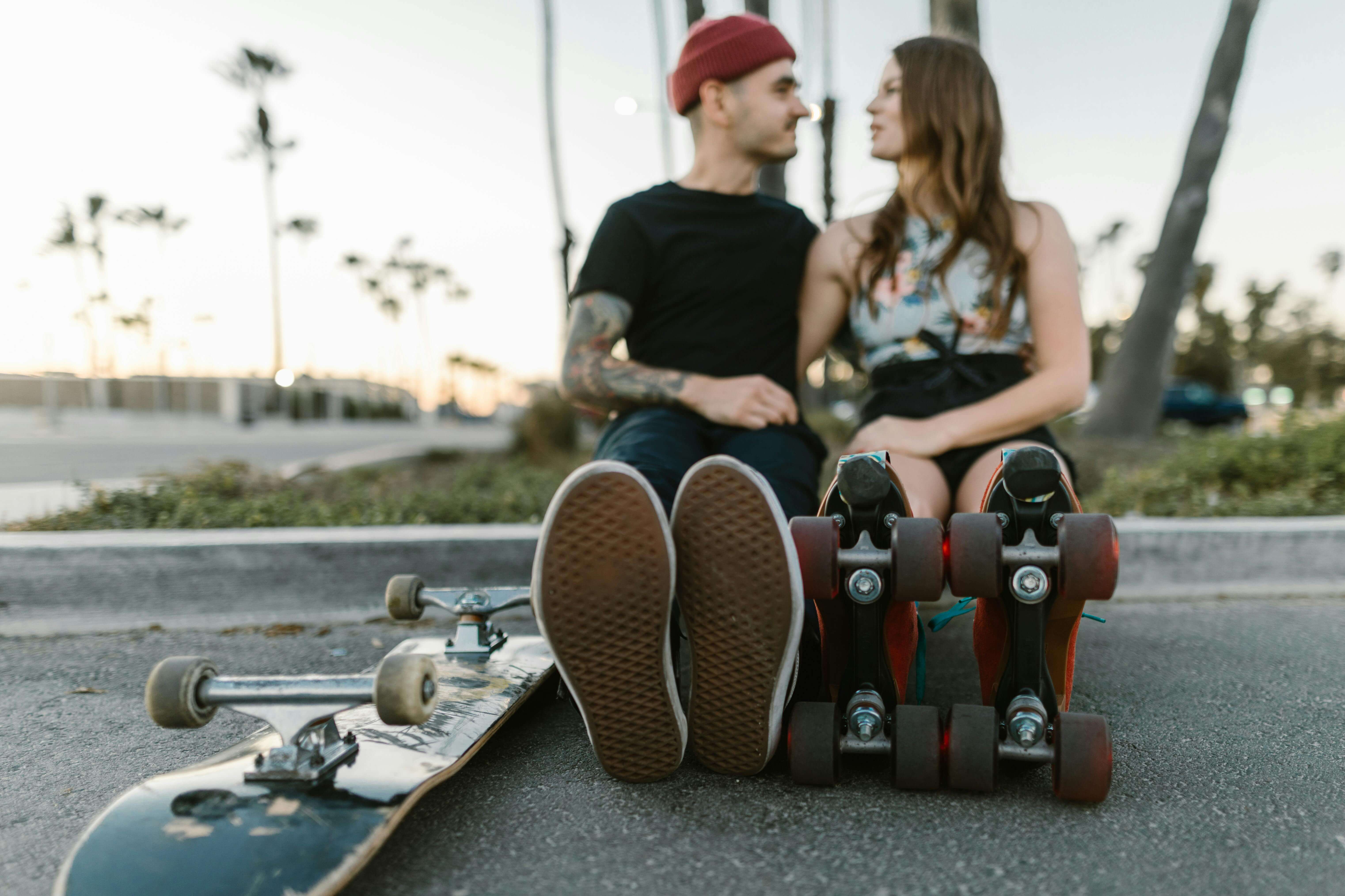 A couple enjoying a romantic moment on skateboards and roller skates outdoors.