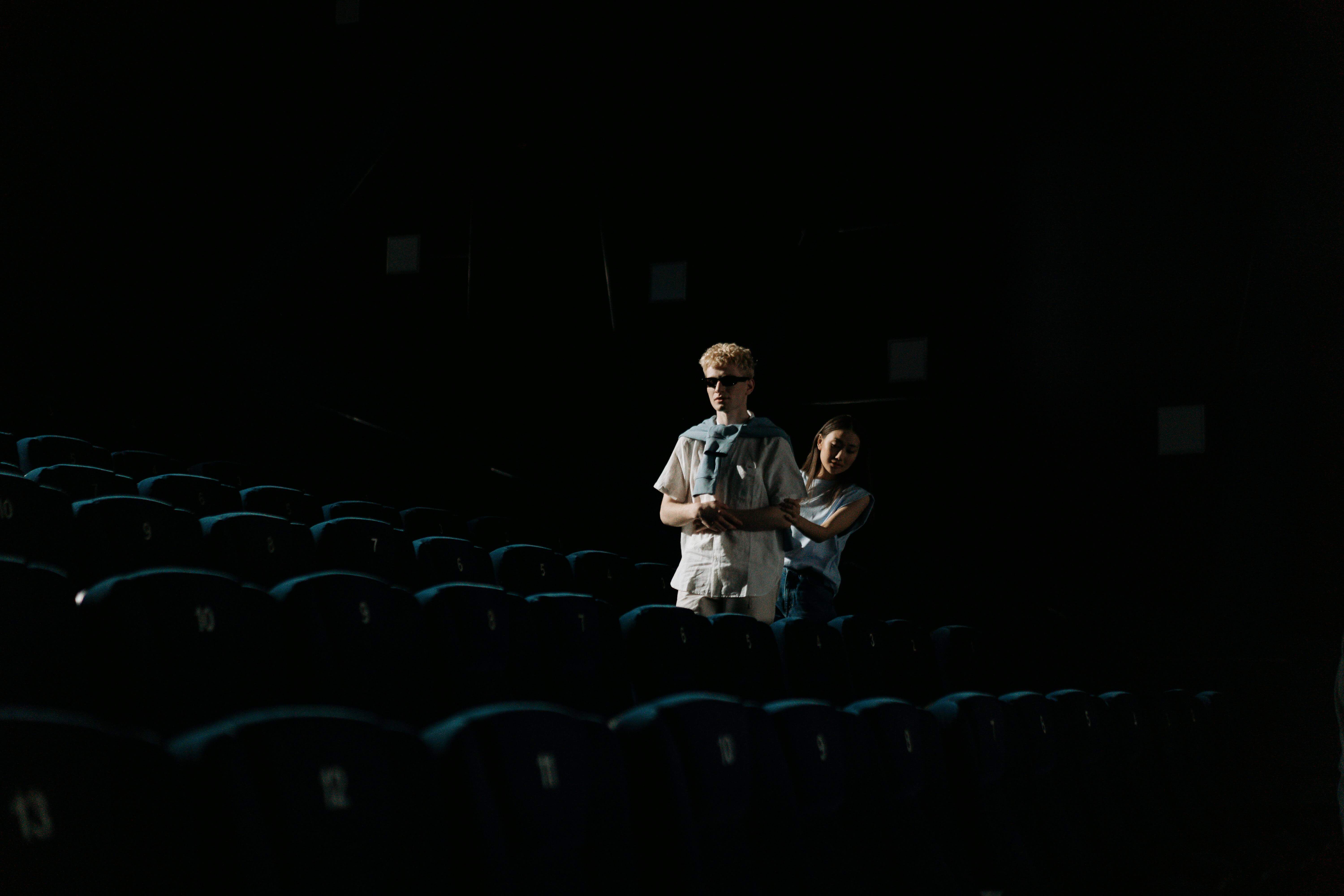 An intimate moment of a couple walking in a dark cinema, capturing the essence of togetherness.