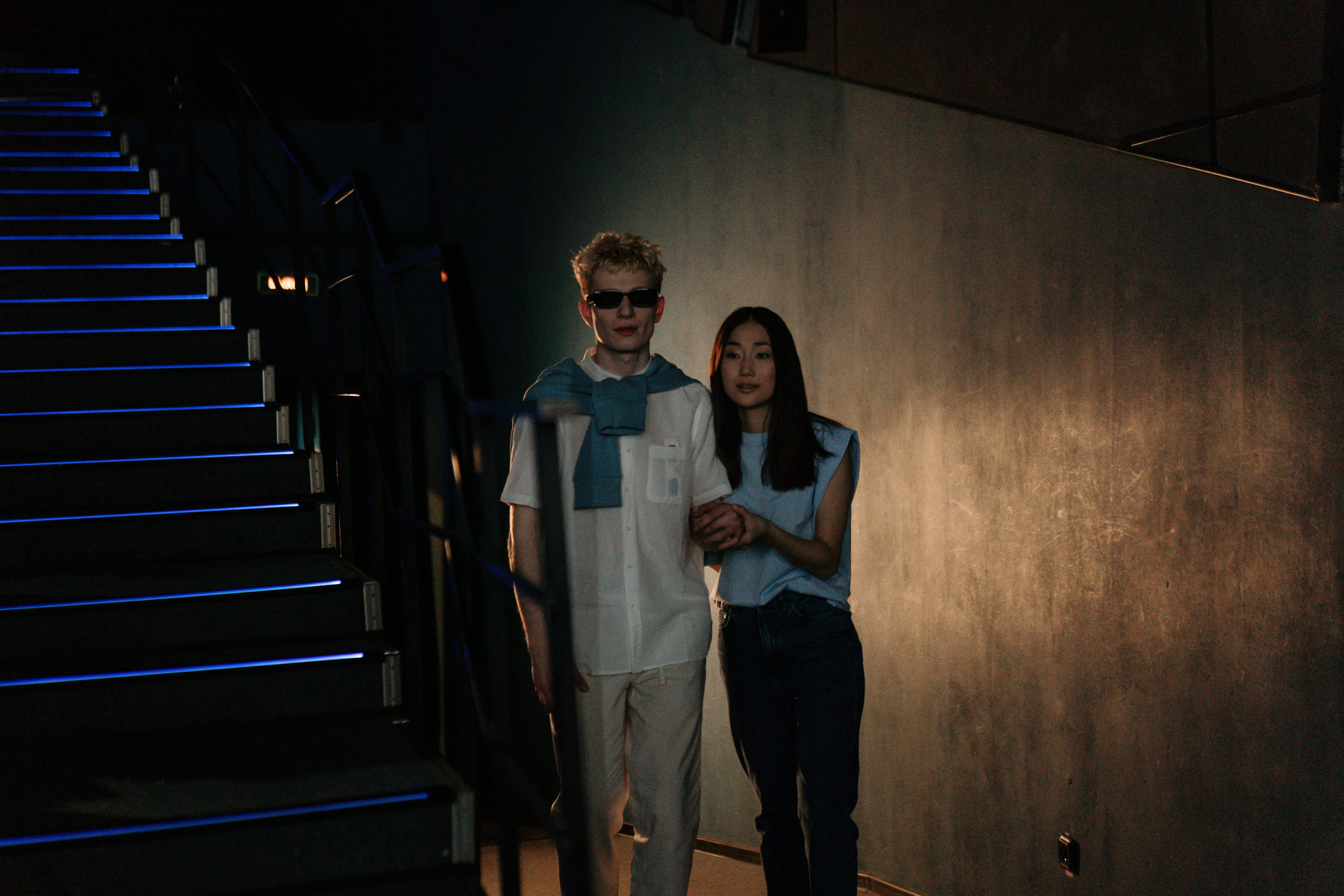 Young couple holding hands and walking down stairs inside a movie theater.