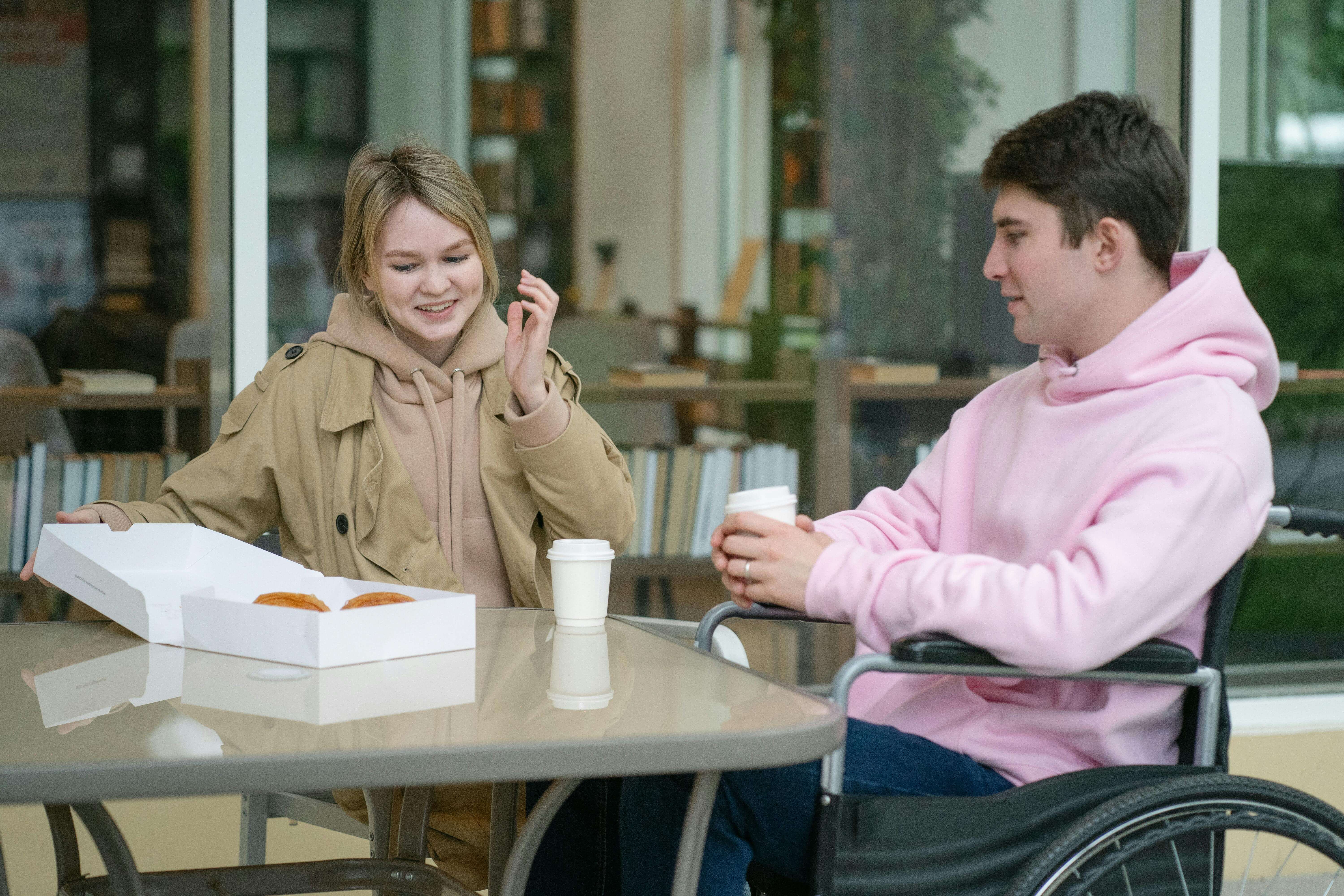 A couple sitting at an outdoor cafÃÂ© table enjoying coffee and pastries in a relaxed setting.