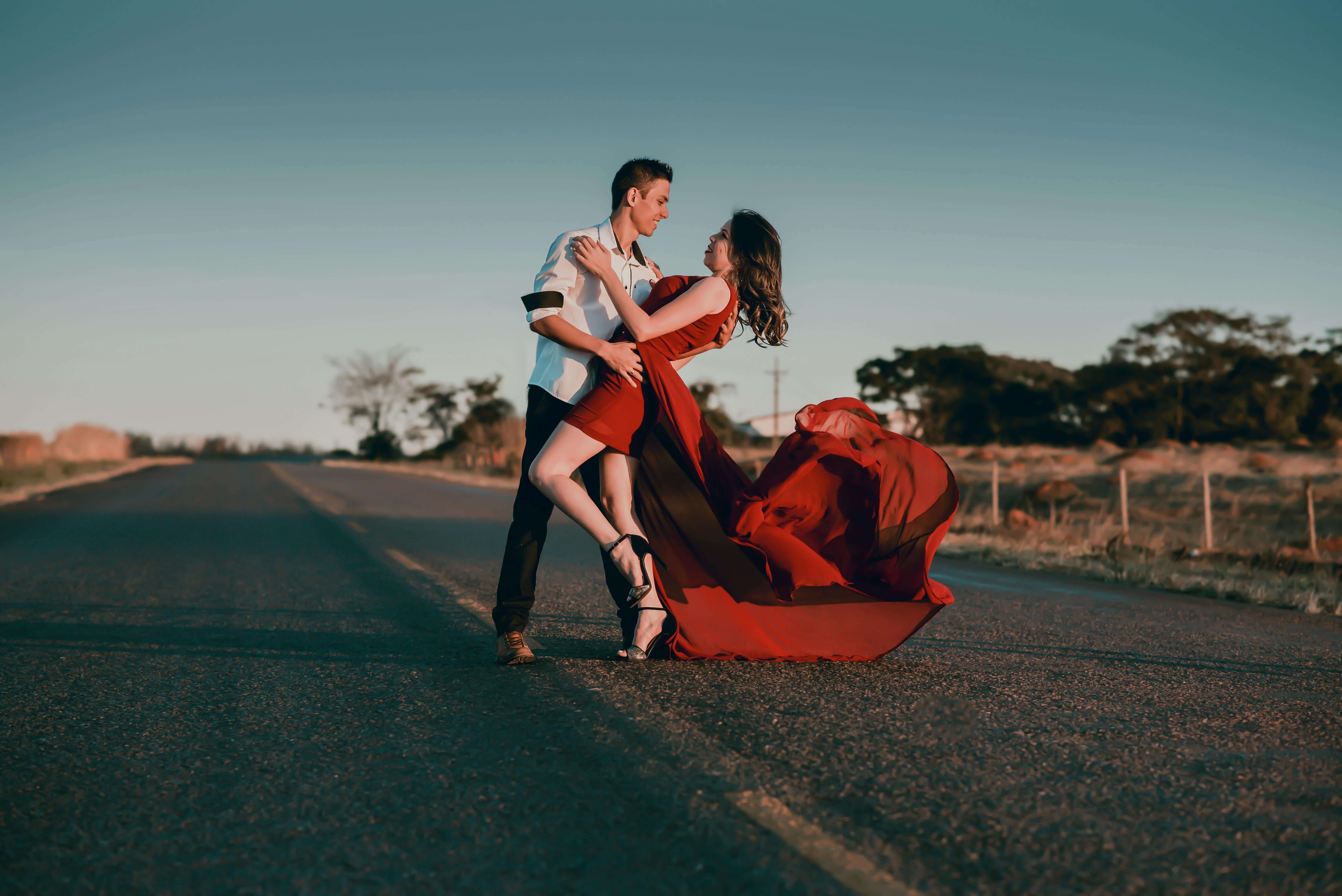 A couple in a passionate dance pose on an empty highway at sunset, showcasing love and romance.