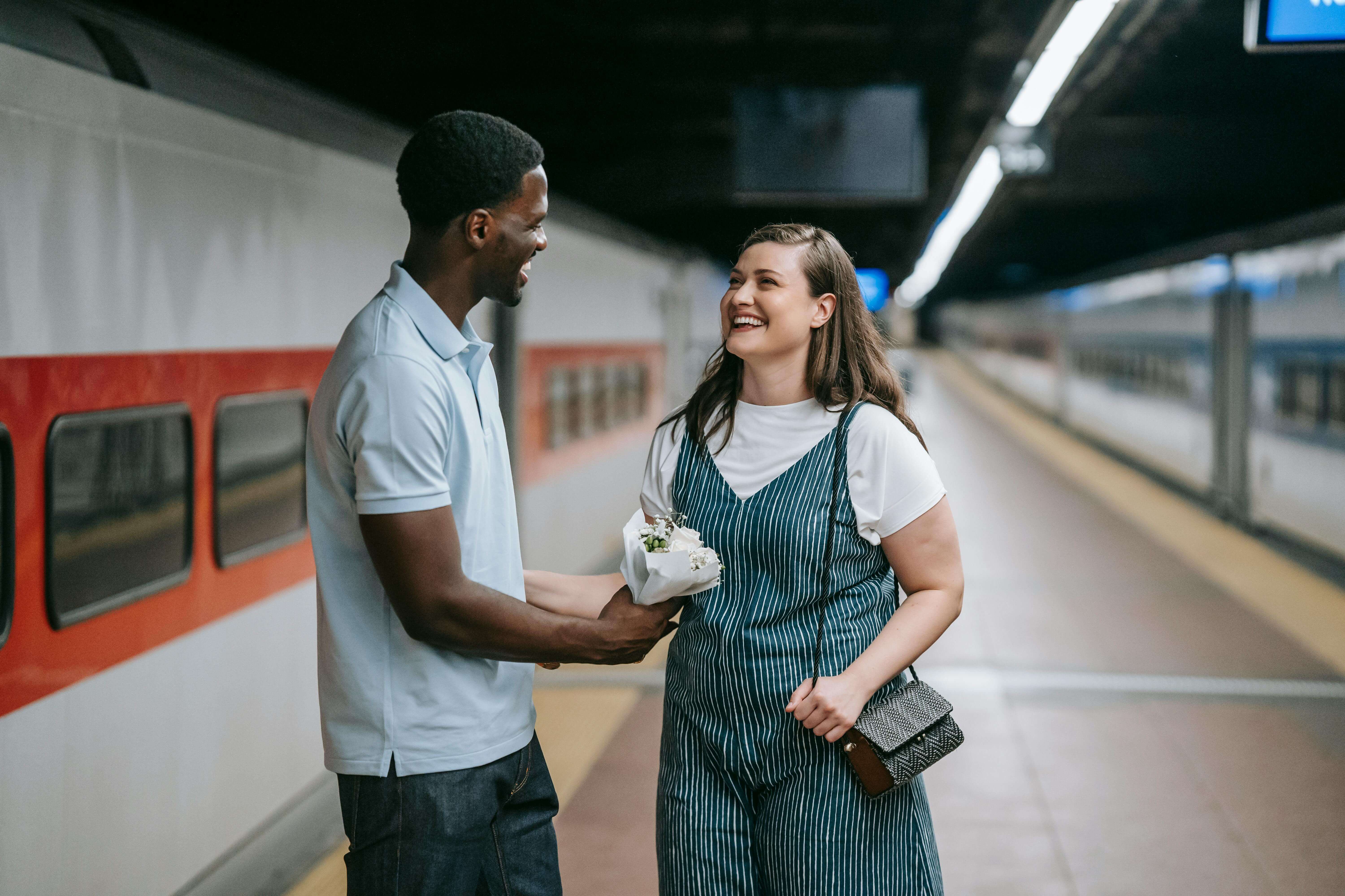 Happy couple sharing a special moment at a train station, conveying love and connection.