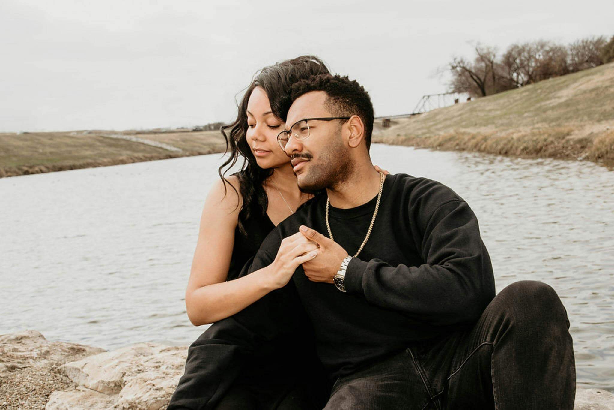 Couple enjoying a tender moment outdoors by a serene lake, showcasing love and togetherness.