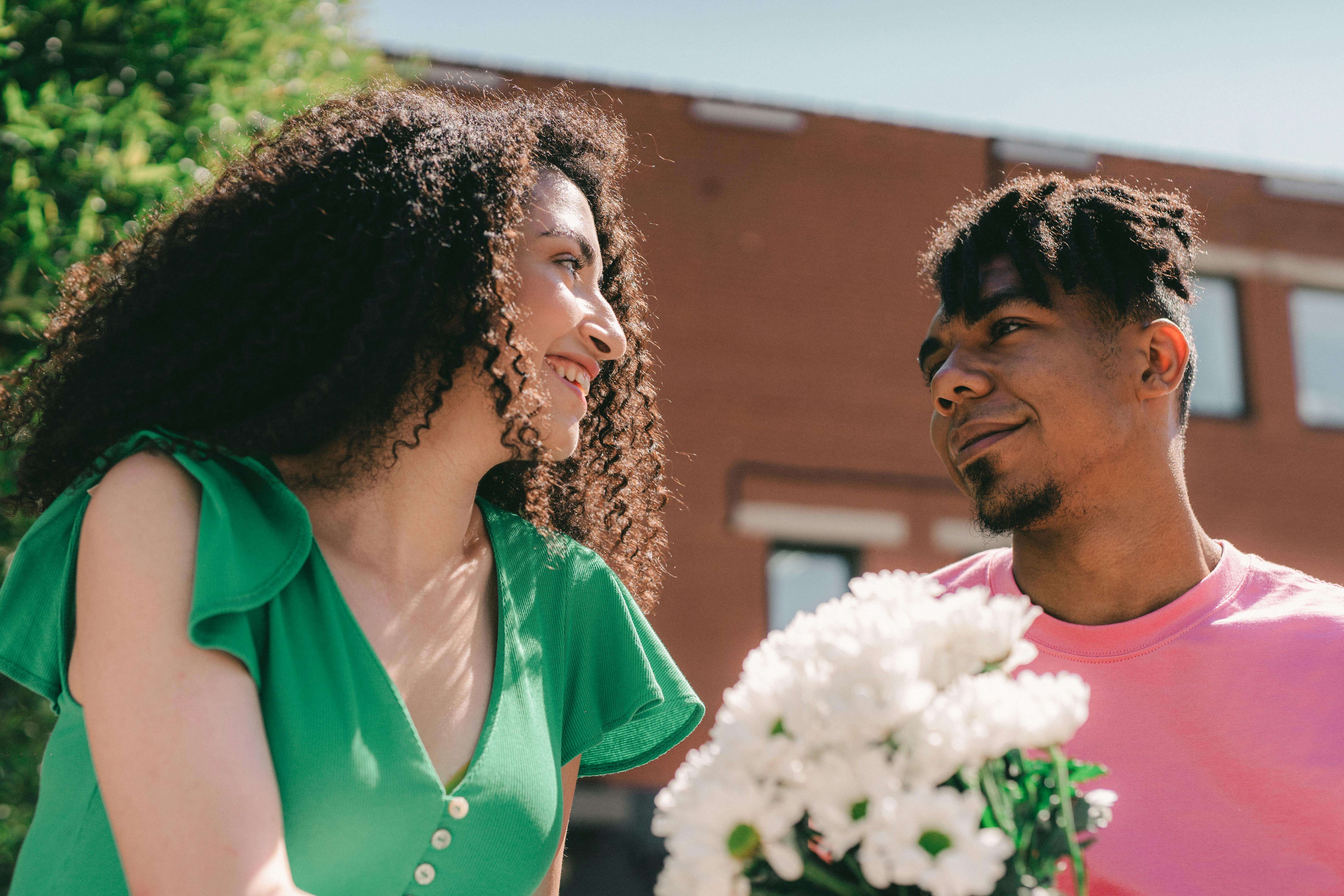Happy couple in love sharing a tender moment with a bouquet of flowers outdoors.