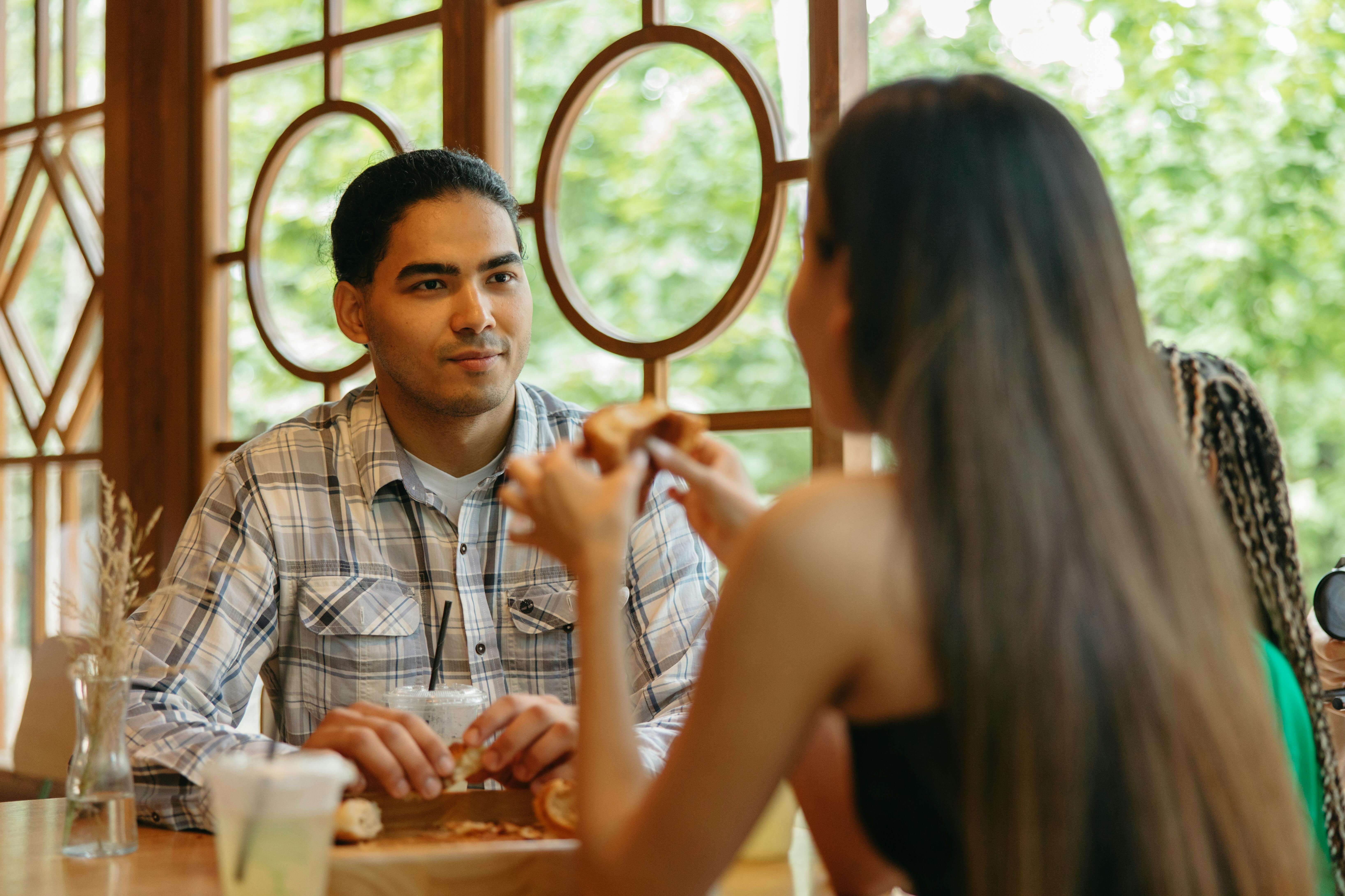Young couple sharing a relaxed lunch in a beautifully lit indoor setting.