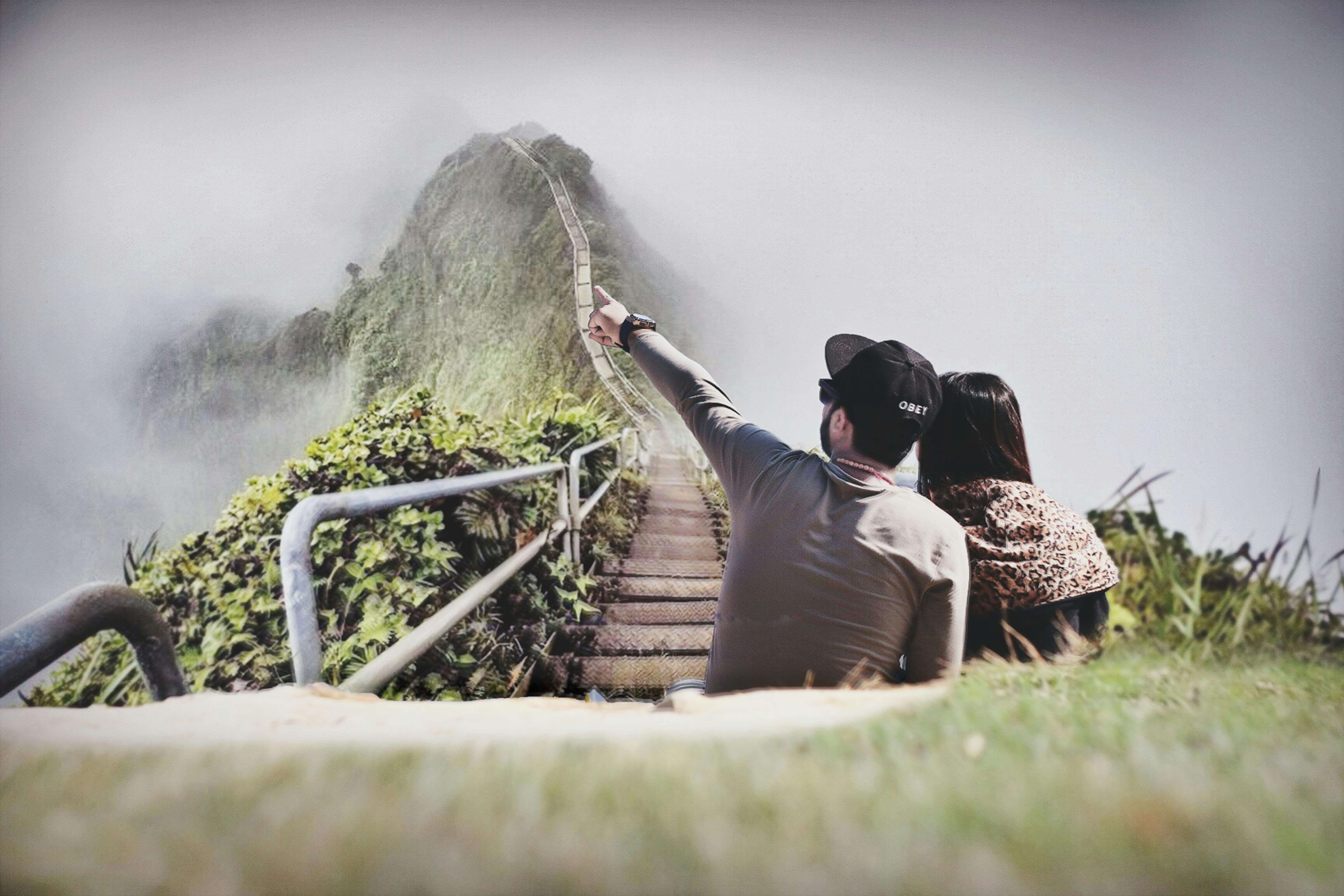 A young couple enjoys the scenic view from a foggy mountain stairway, embracing nature's beauty.