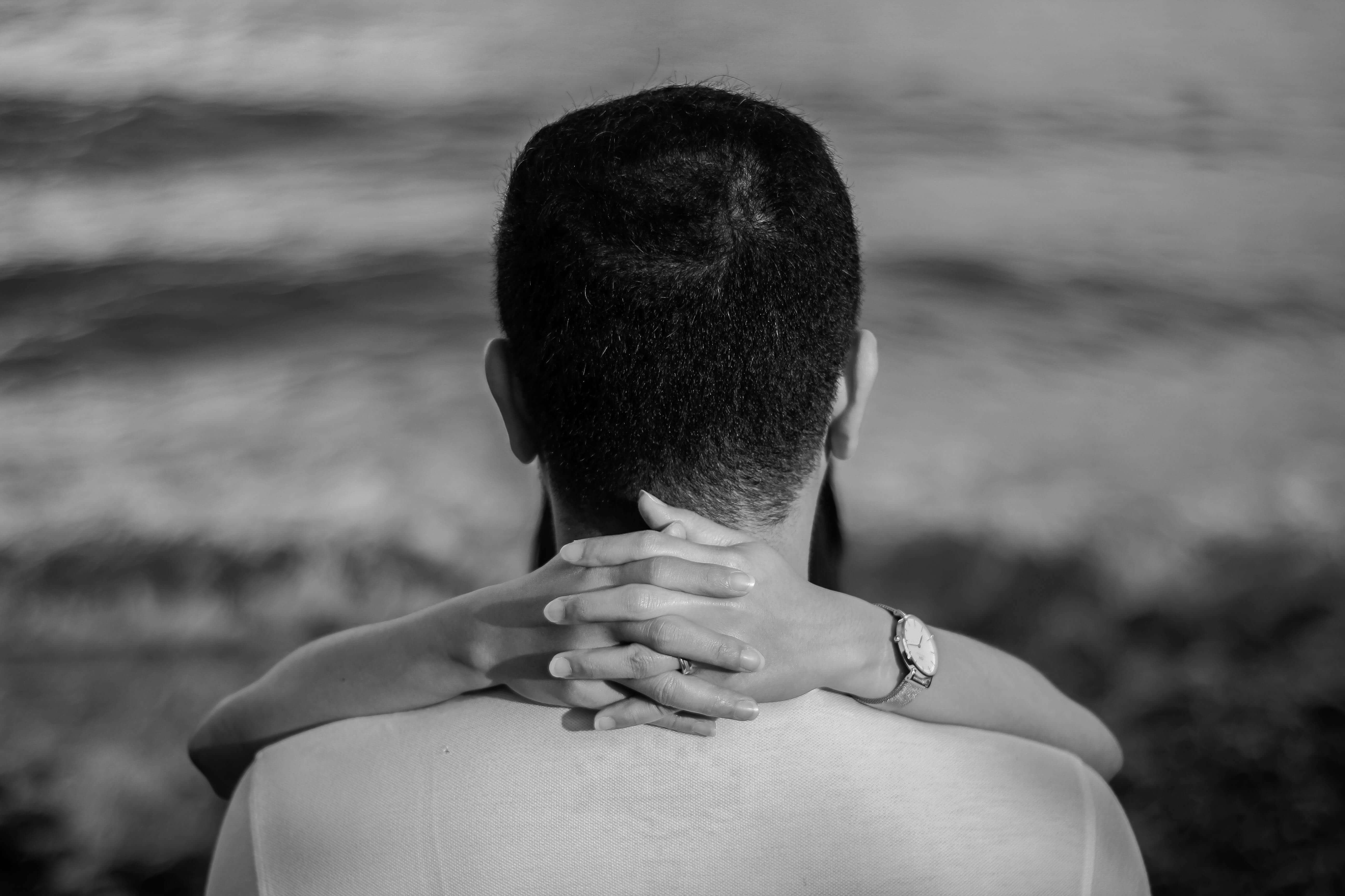 A monochrome image of a couple hugging at the beach, emphasizing romance and tranquility.