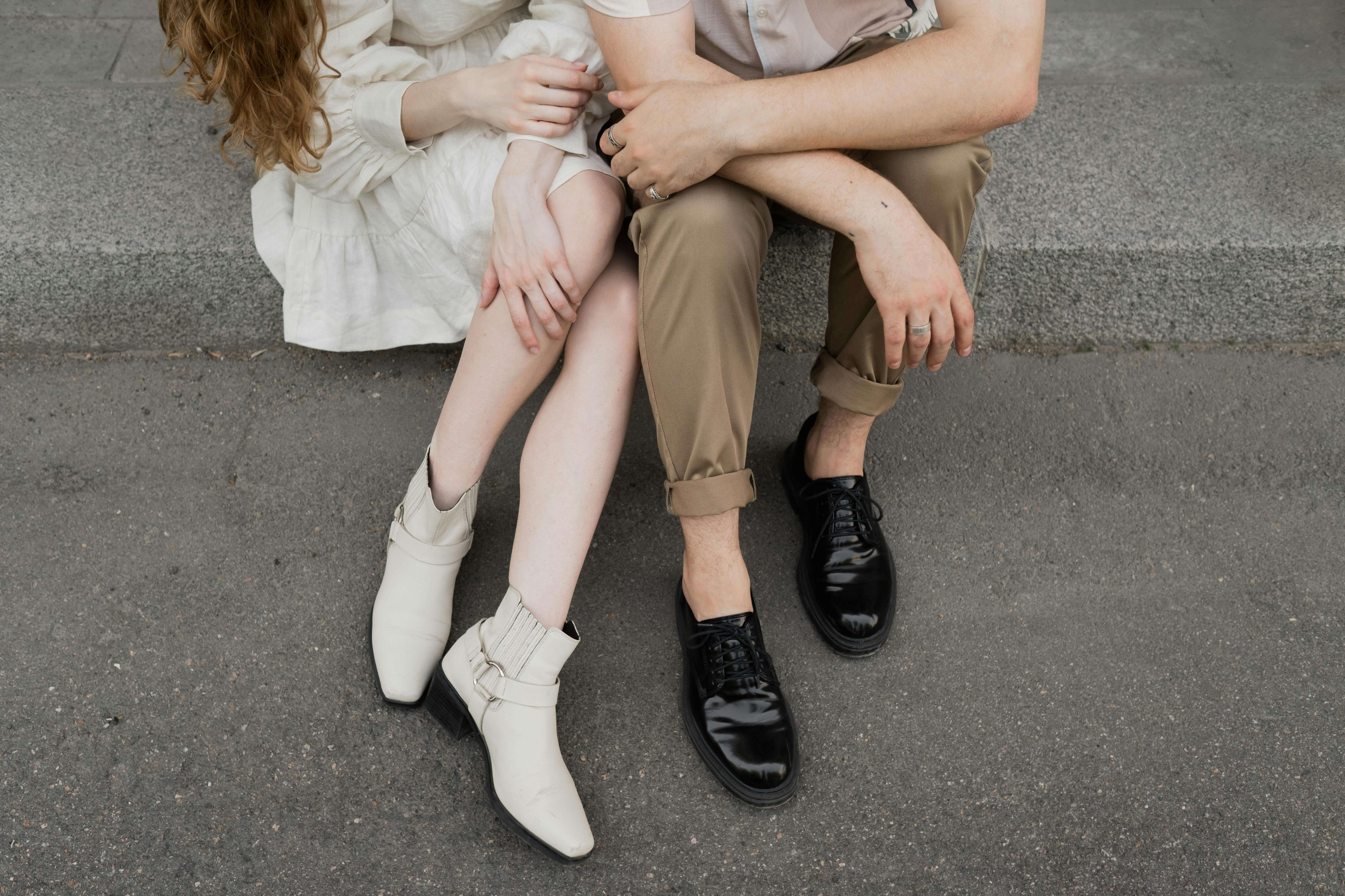 Close-up of a couple sitting together, highlighting their legs and casual outfits.