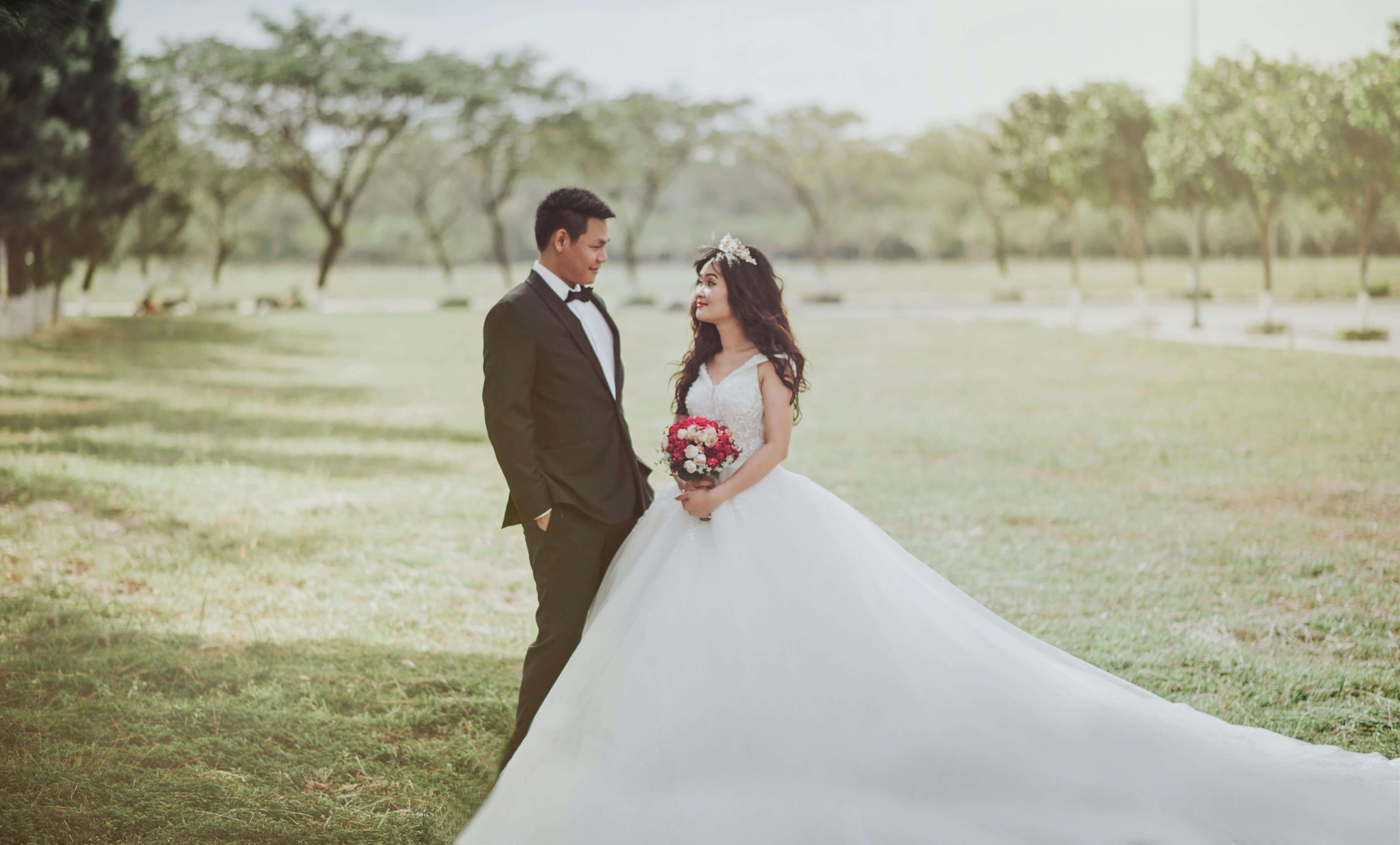 Romantic outdoor wedding photoshoot of a bride and groom in a serene park setting.