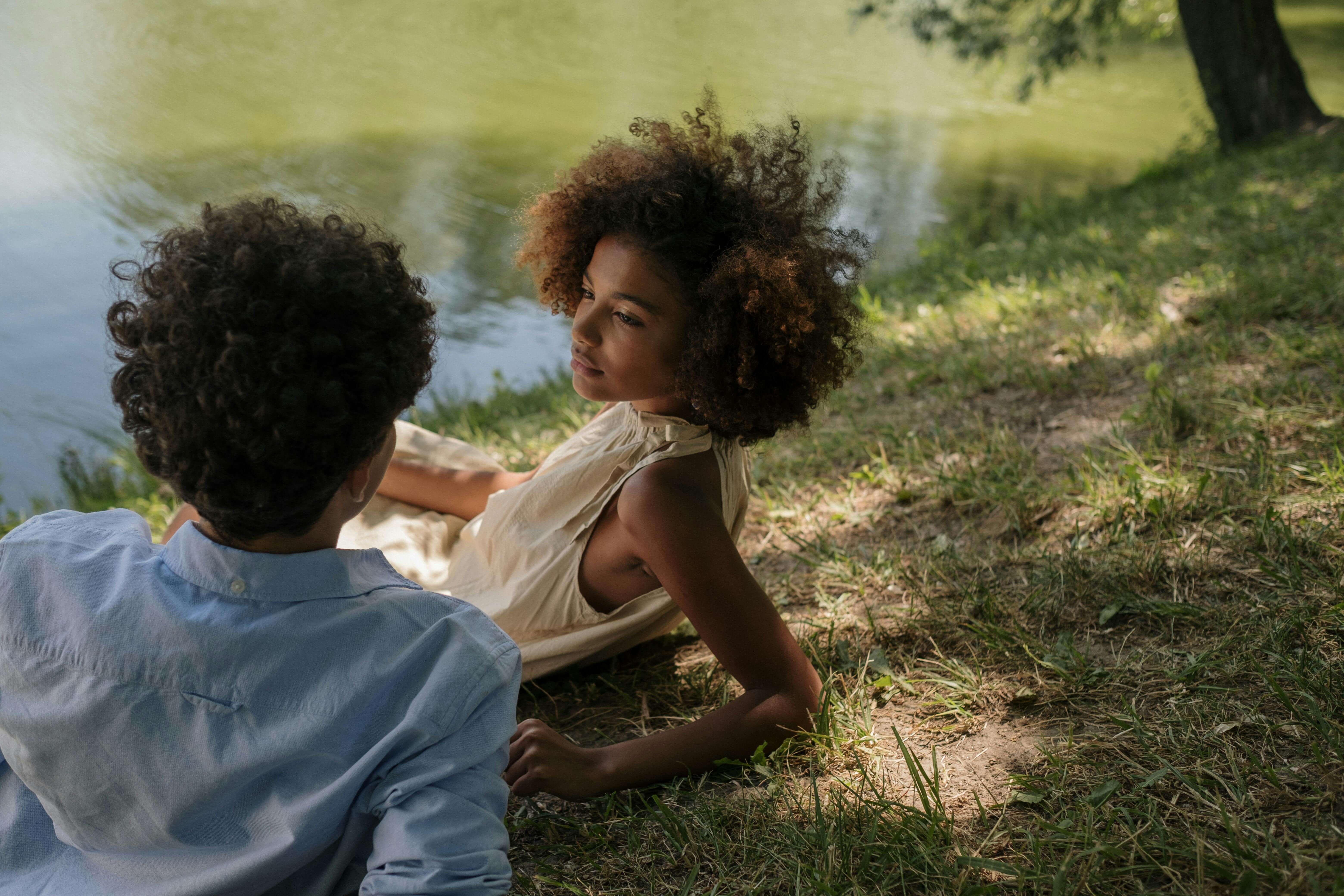 Teenage couple enjoying a serene moment together by the lakeside on a sunny day.