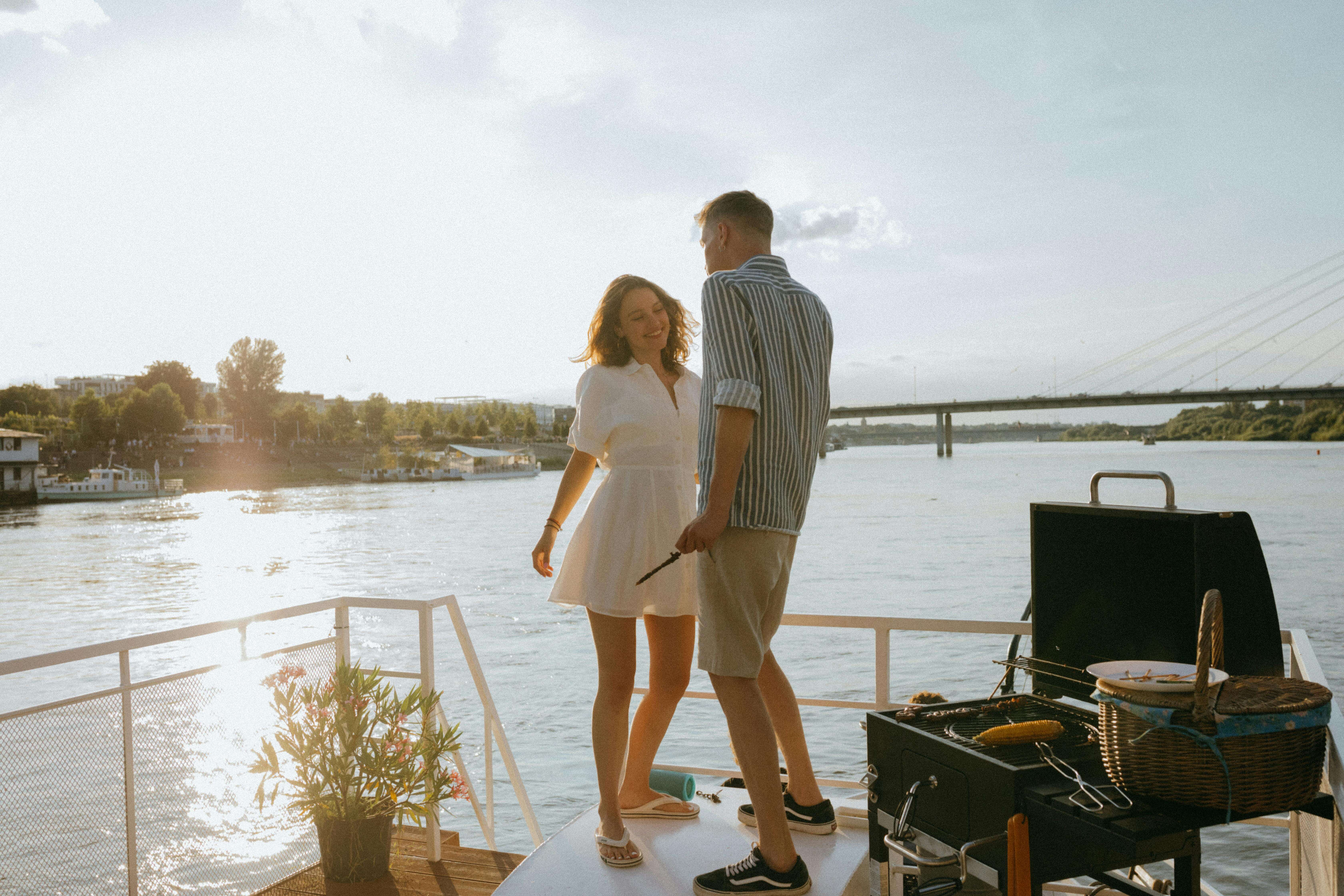 A young couple enjoying a romantic barbecue on a yacht during a beautiful summer sunset.