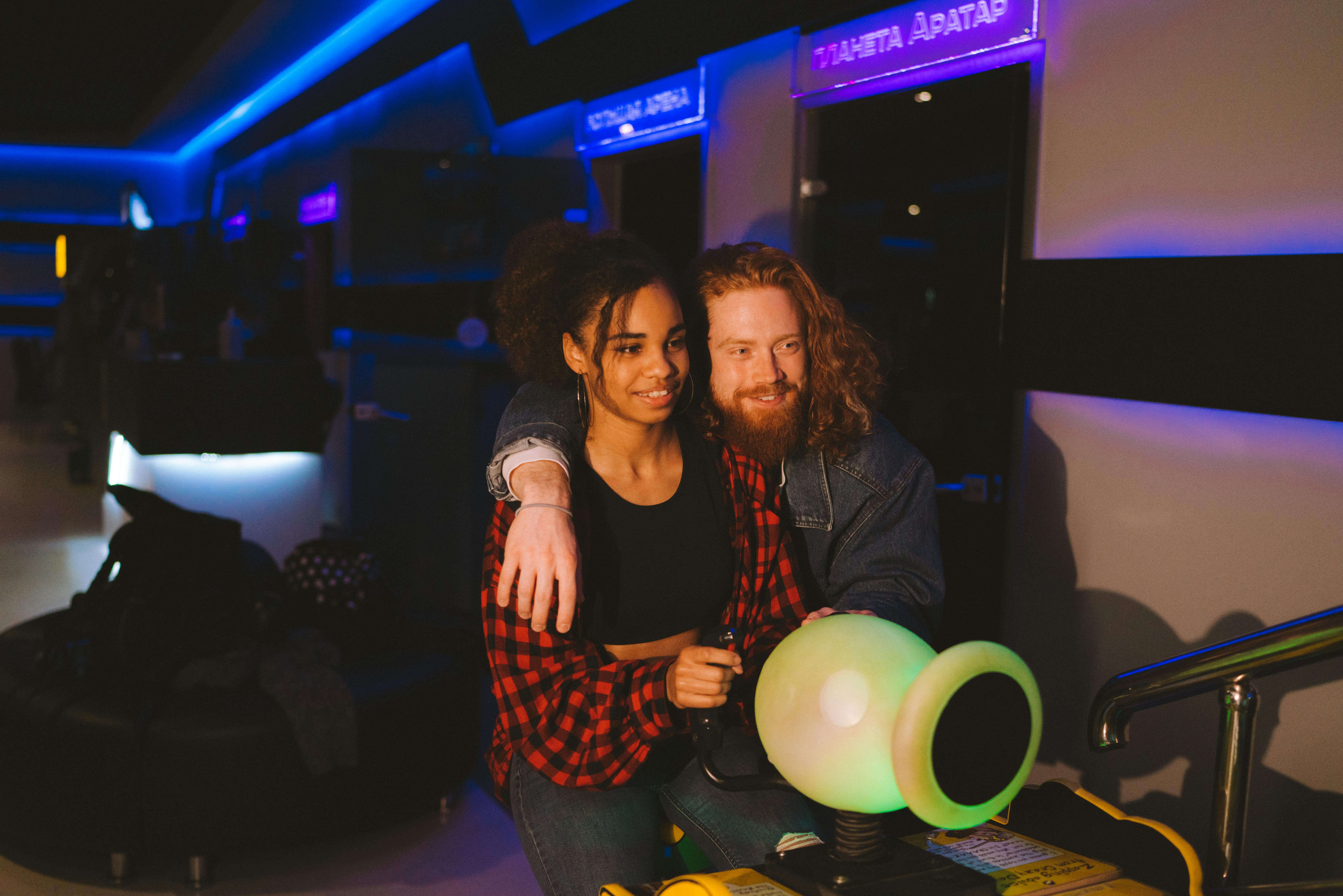 Happy couple having fun at an illuminated indoor arcade.