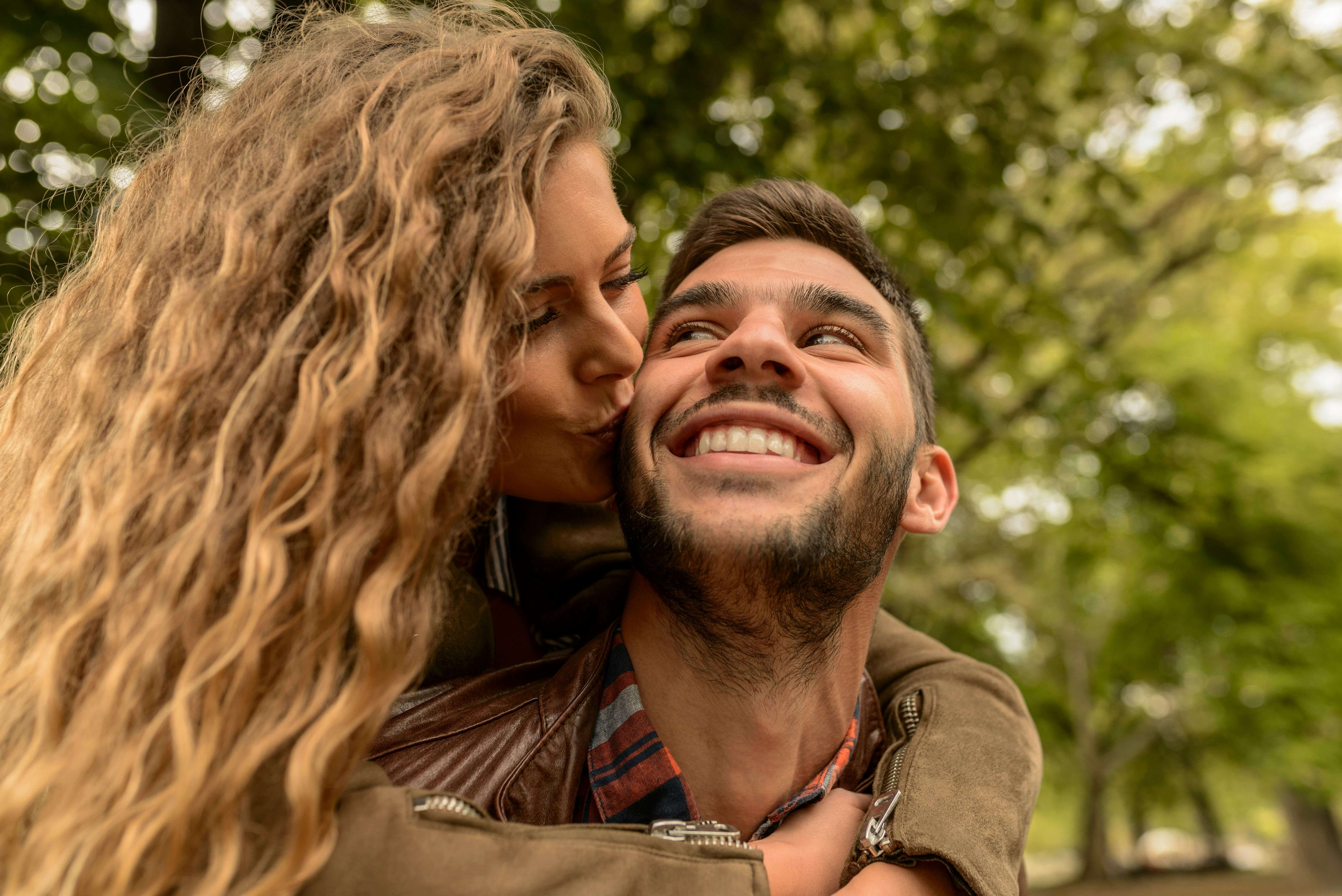 Happy couple enjoying affectionate moment outdoors in a lush green park.