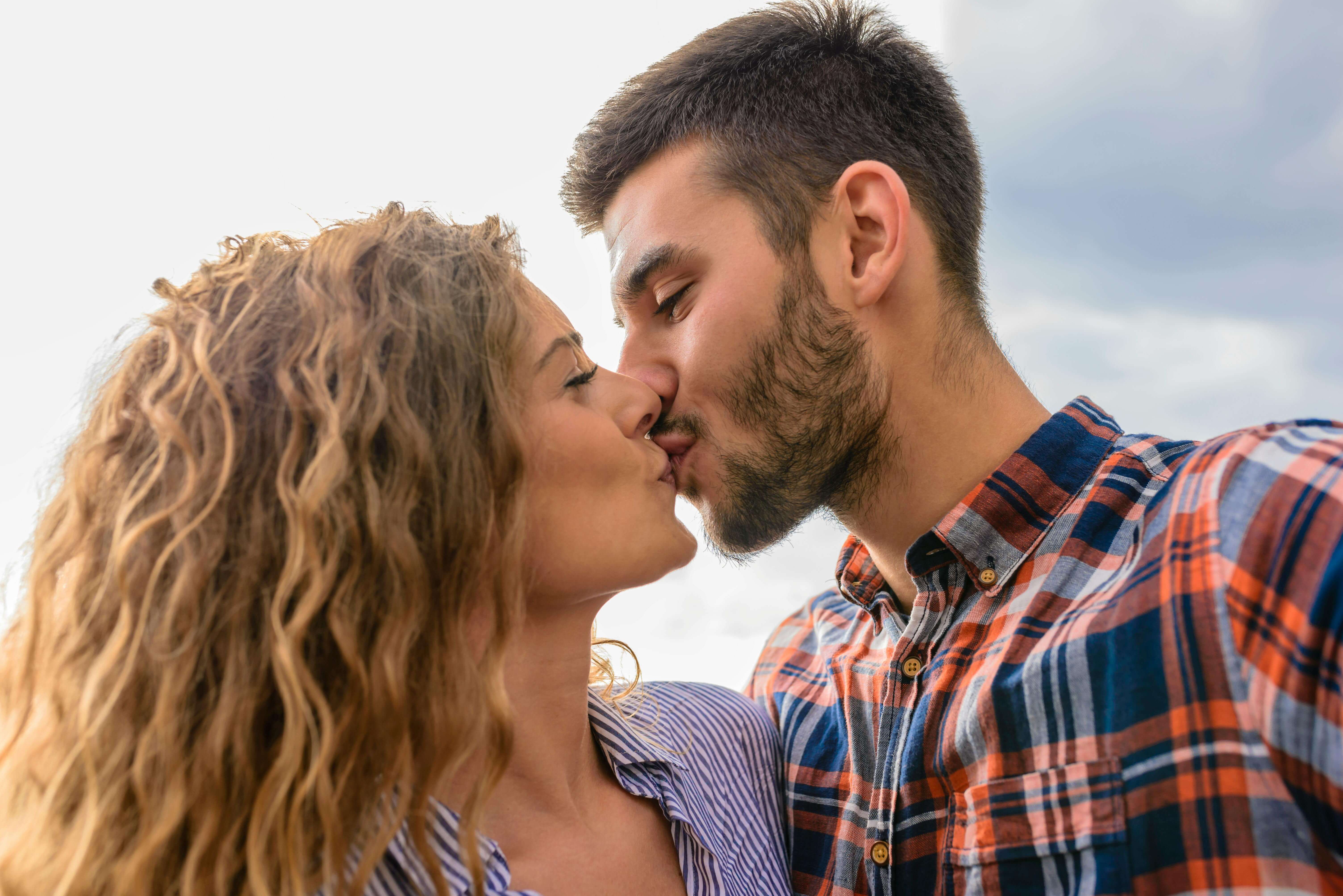 A young couple kisses passionately against an outdoor backdrop, symbolizing love and togetherness.